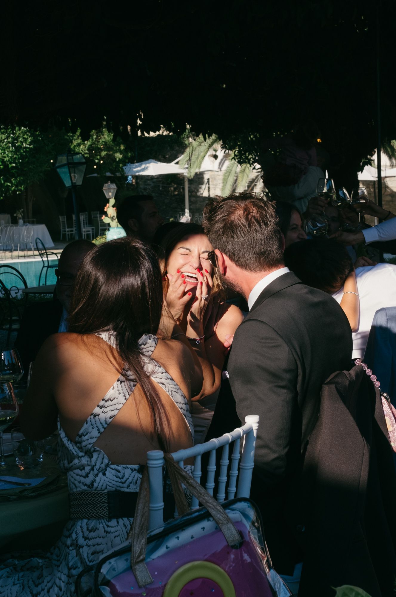 Wedding guests enjoying a lively moment at an outdoor evening reception with ambient lighting.