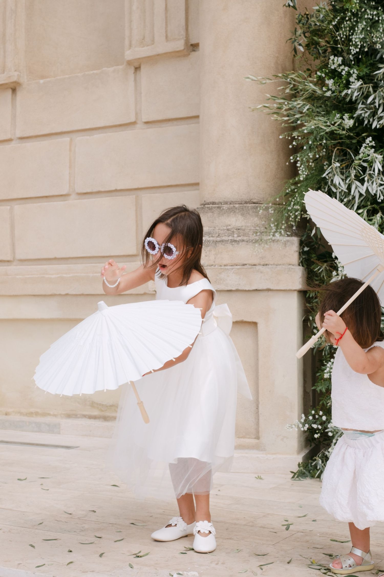 Artistic sequence of a dancer in white dress twirling gracefully against a light stone building facade.