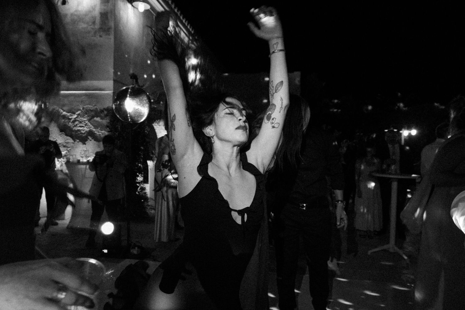 Dark nighttime celebration with dancing guests and party lighting.