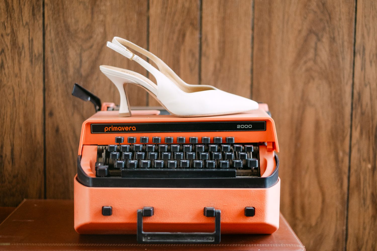 Vintage orange typewriter on rustic wooden surface shown from multiple angles in a collage format.