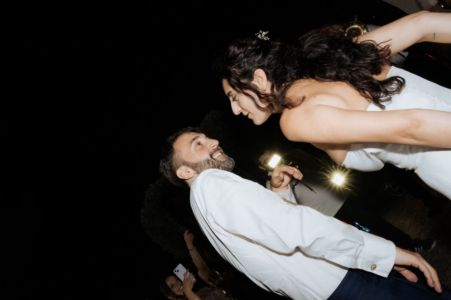 Dynamic dance floor moments captured at a dimly lit wedding reception celebration.