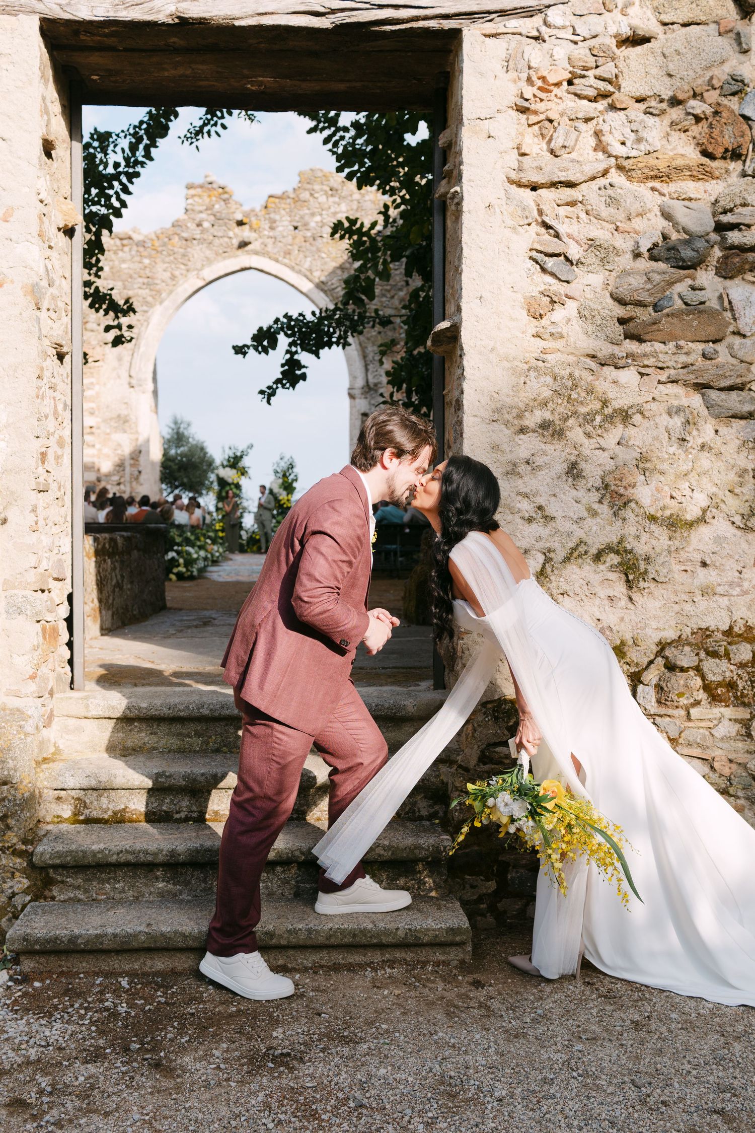 Sequence showing wedding dress being carefully lifted over stone steps at historic venue.
