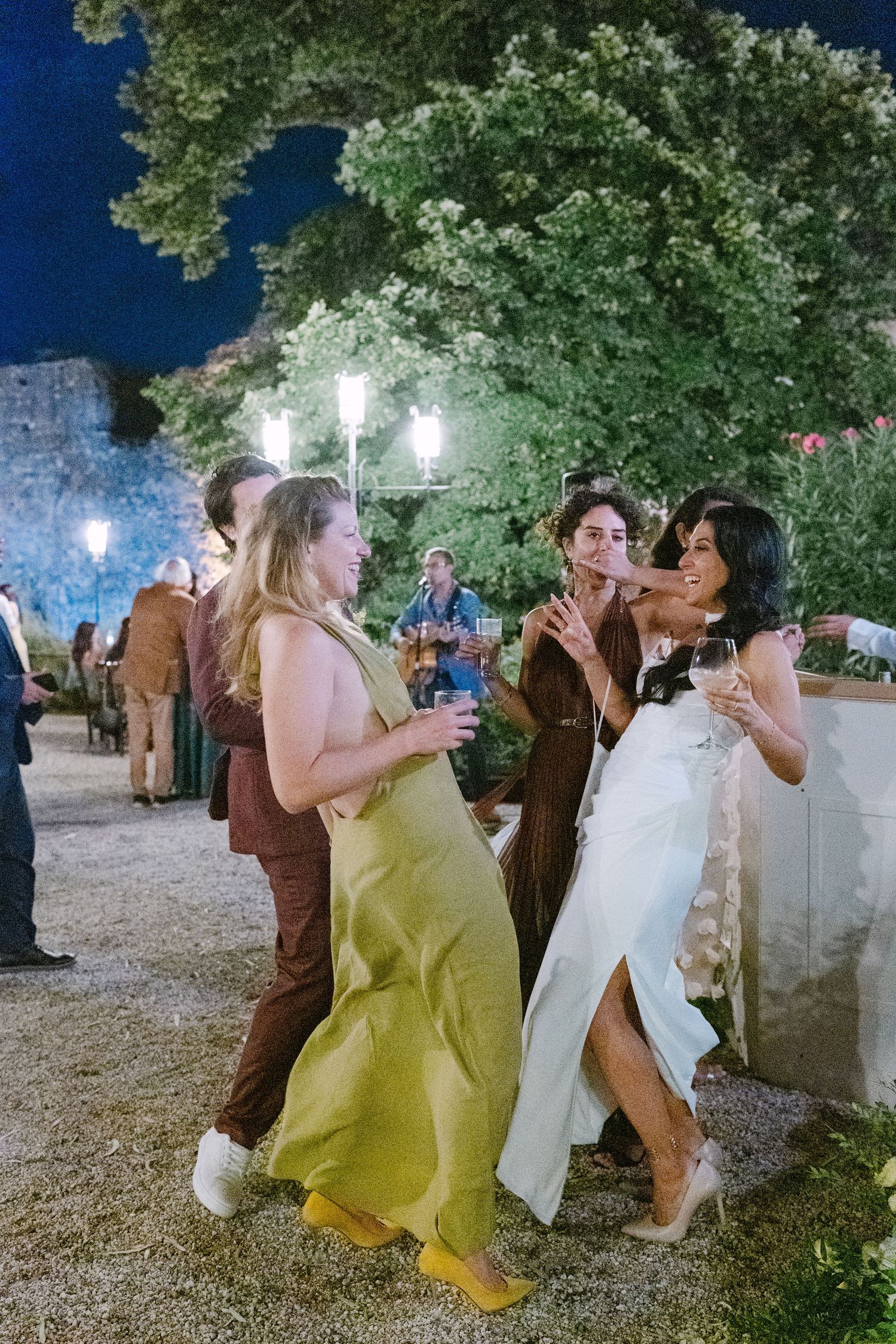 Wedding guests dancing outdoors at night under string lights.