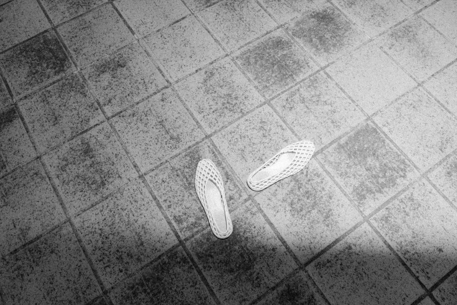 Black and white artistic photograph of shoes on tiled floor.