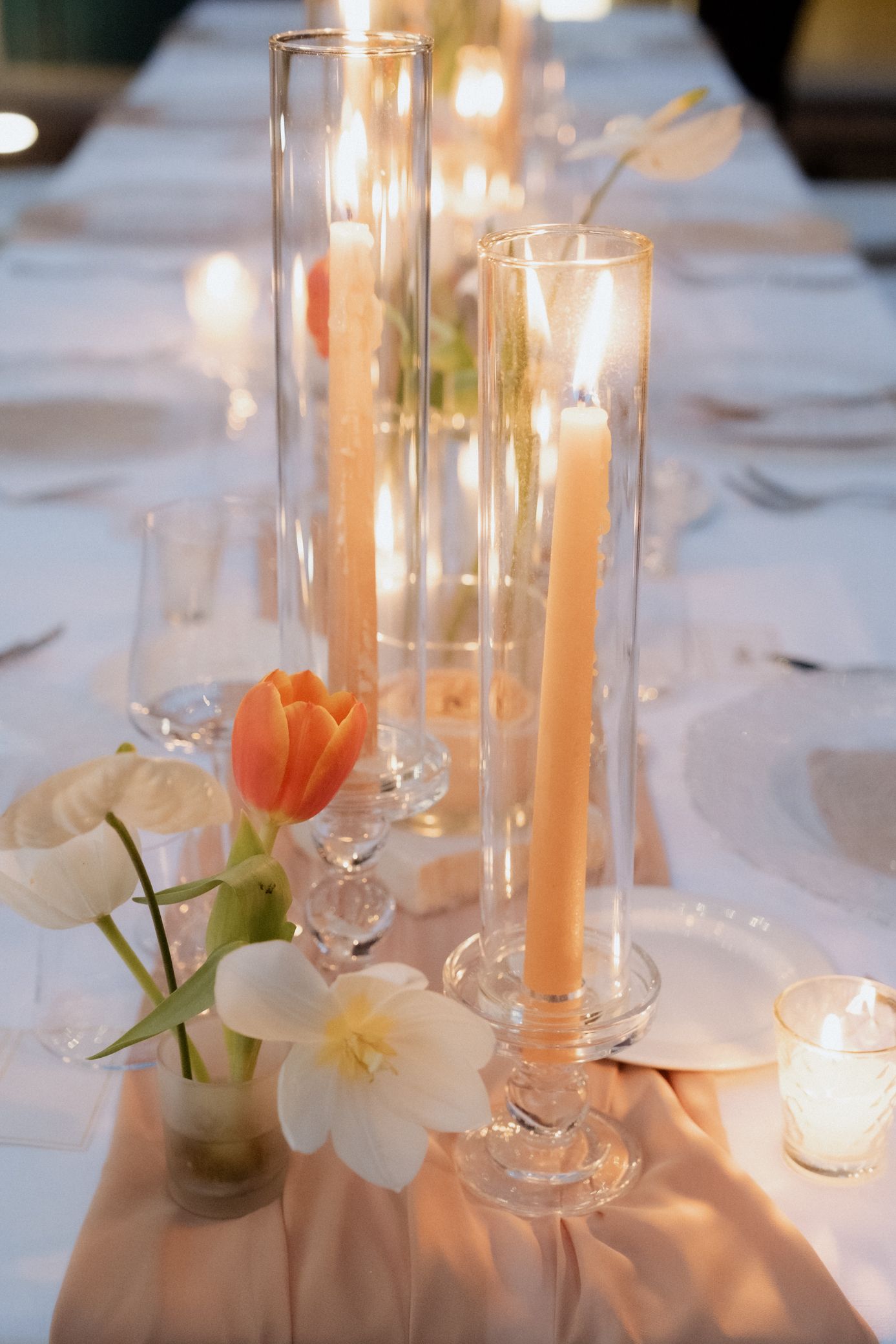 Elegant wedding table decor with glowing candles in glass holders and delicate white orchids creating a romantic ambiance.