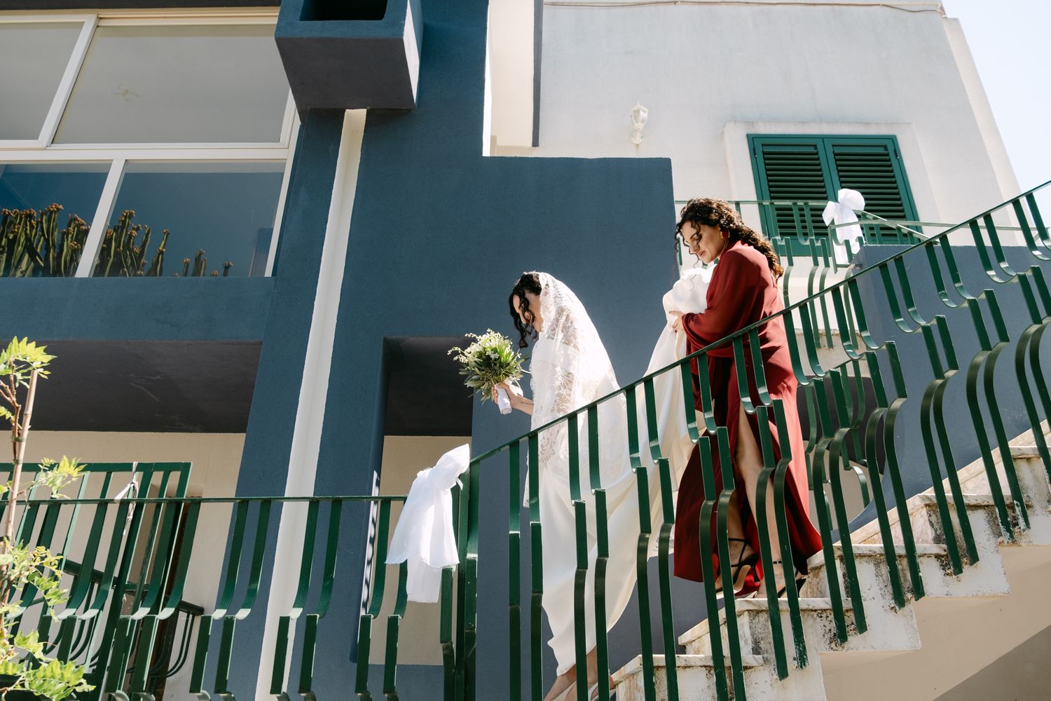 Empty green chairs line a white balcony with ocean views.