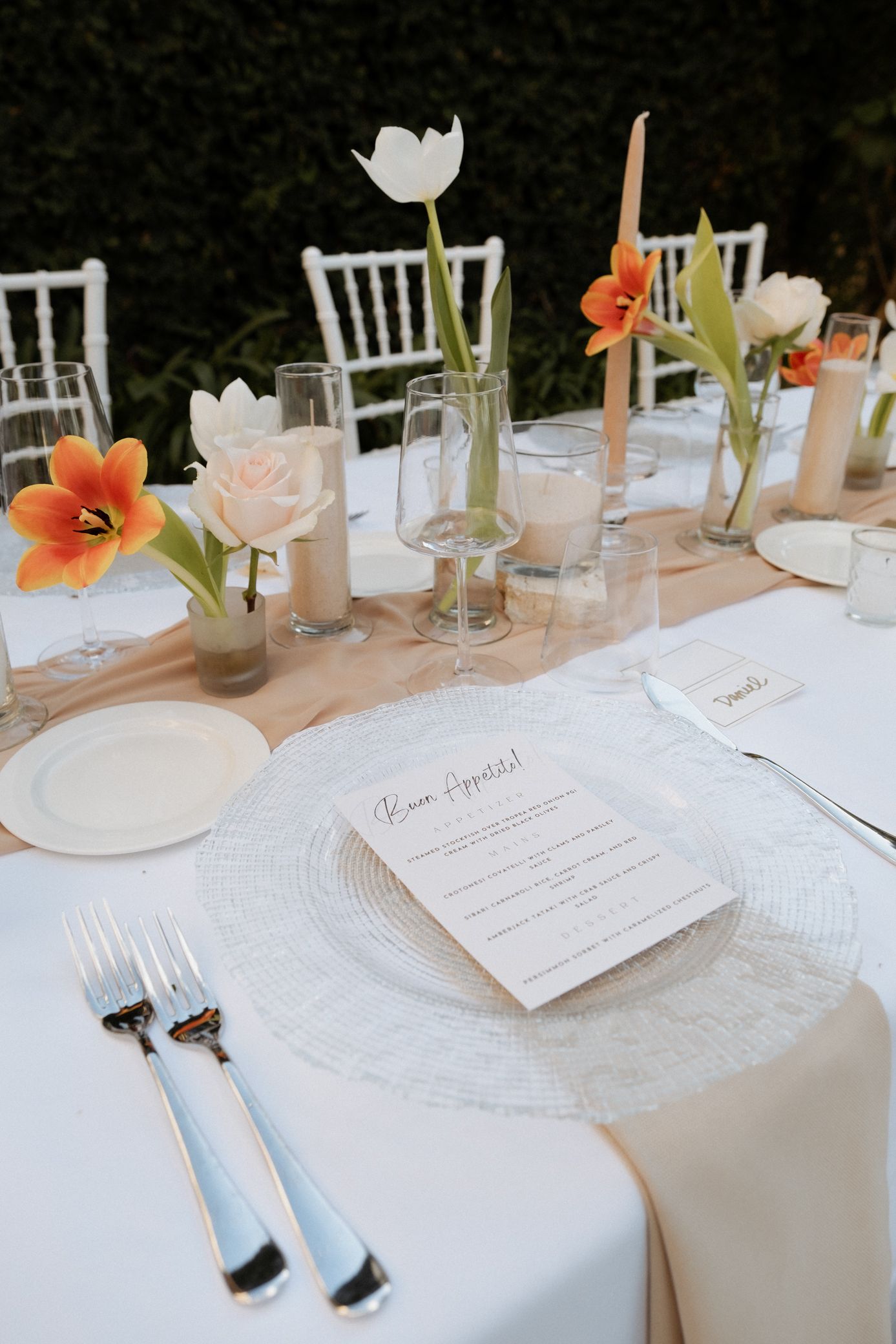Elegant white table settings with tulips and place cards arranged for a formal dining event or wedding reception.