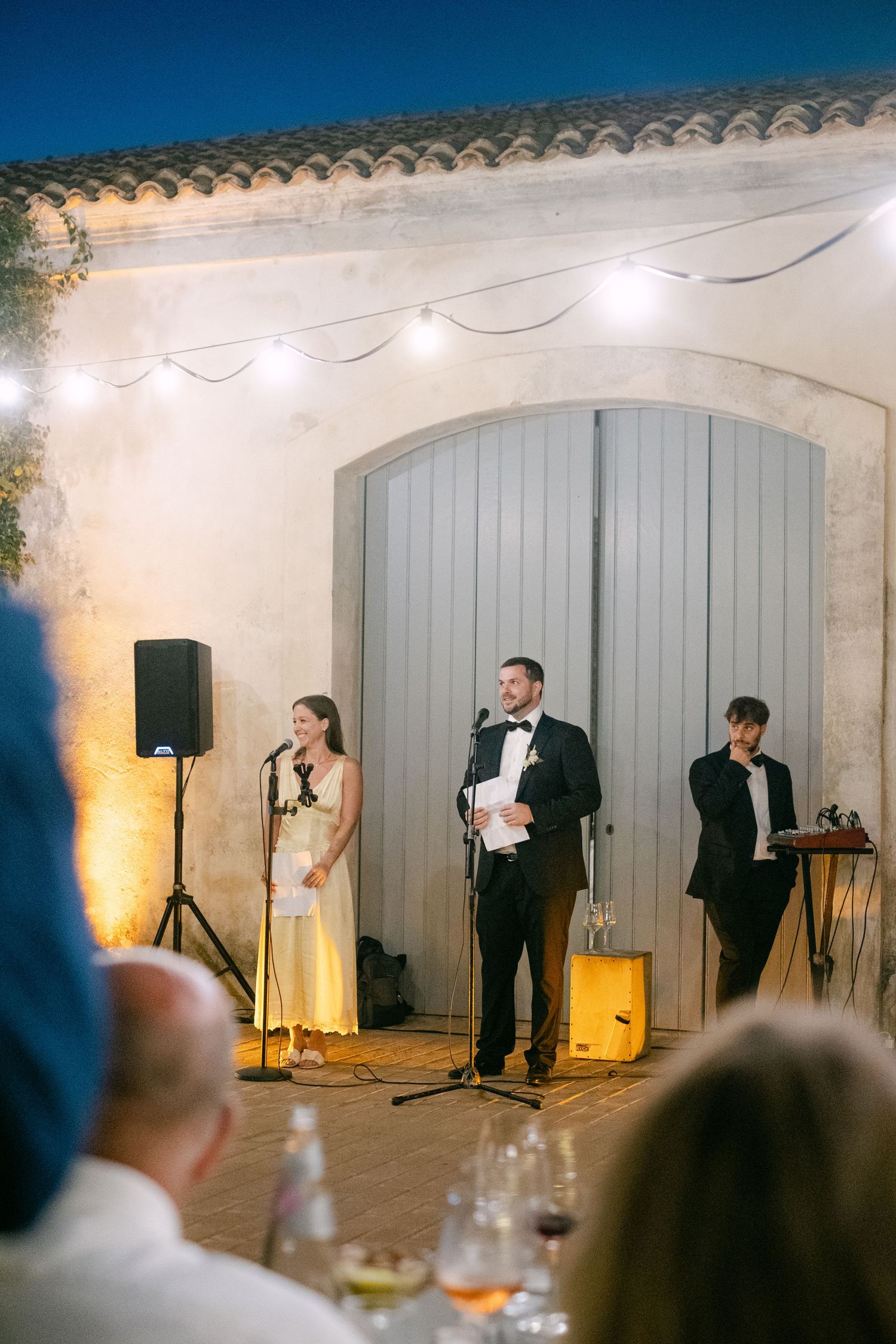 Wedding reception entertainment performance in front of gray barn doors with ambient lighting.