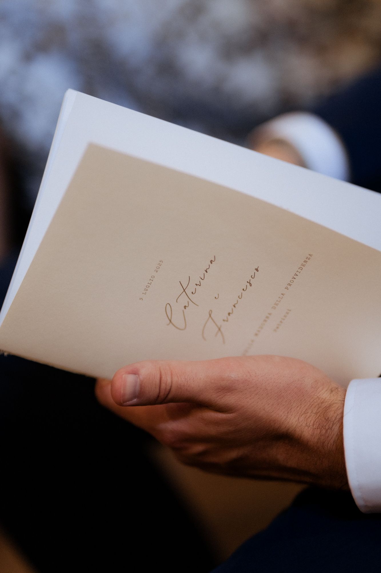 Close-up shot of hands holding a wedding ceremony program or order of service.