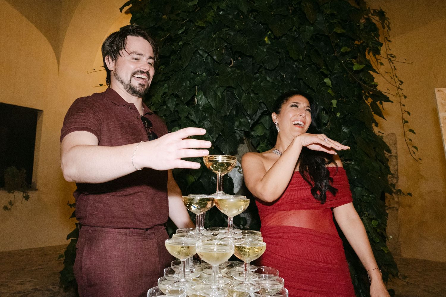 A group of people in formal attire share drinks and laughter at an elegant party setting.