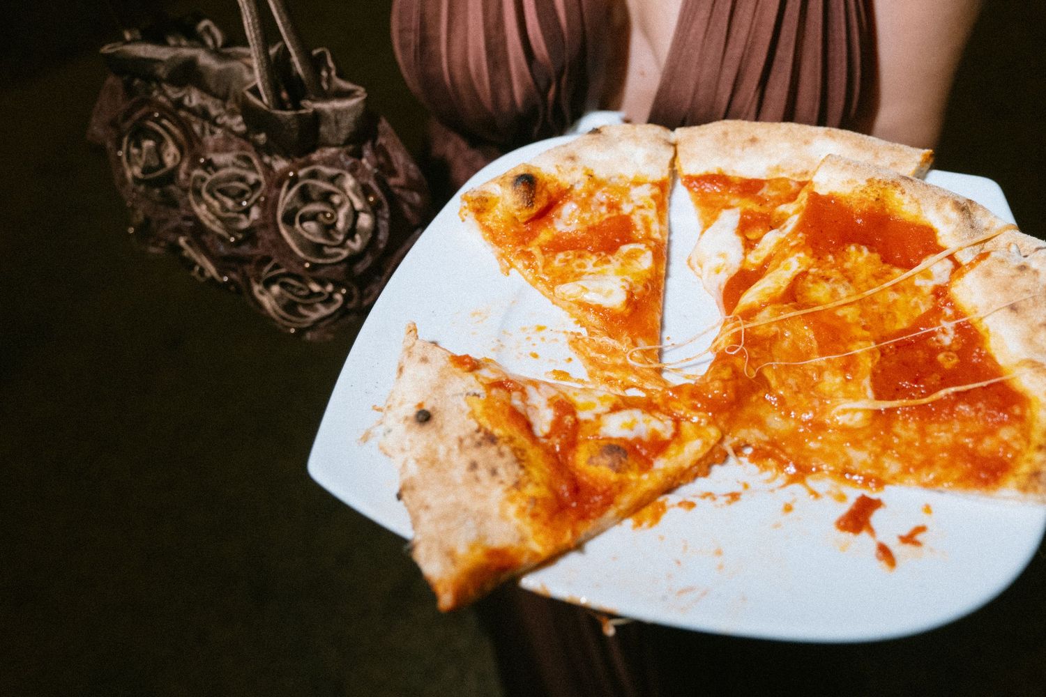 Close-up view of partially eaten pizza slices on white plates at a wedding reception.