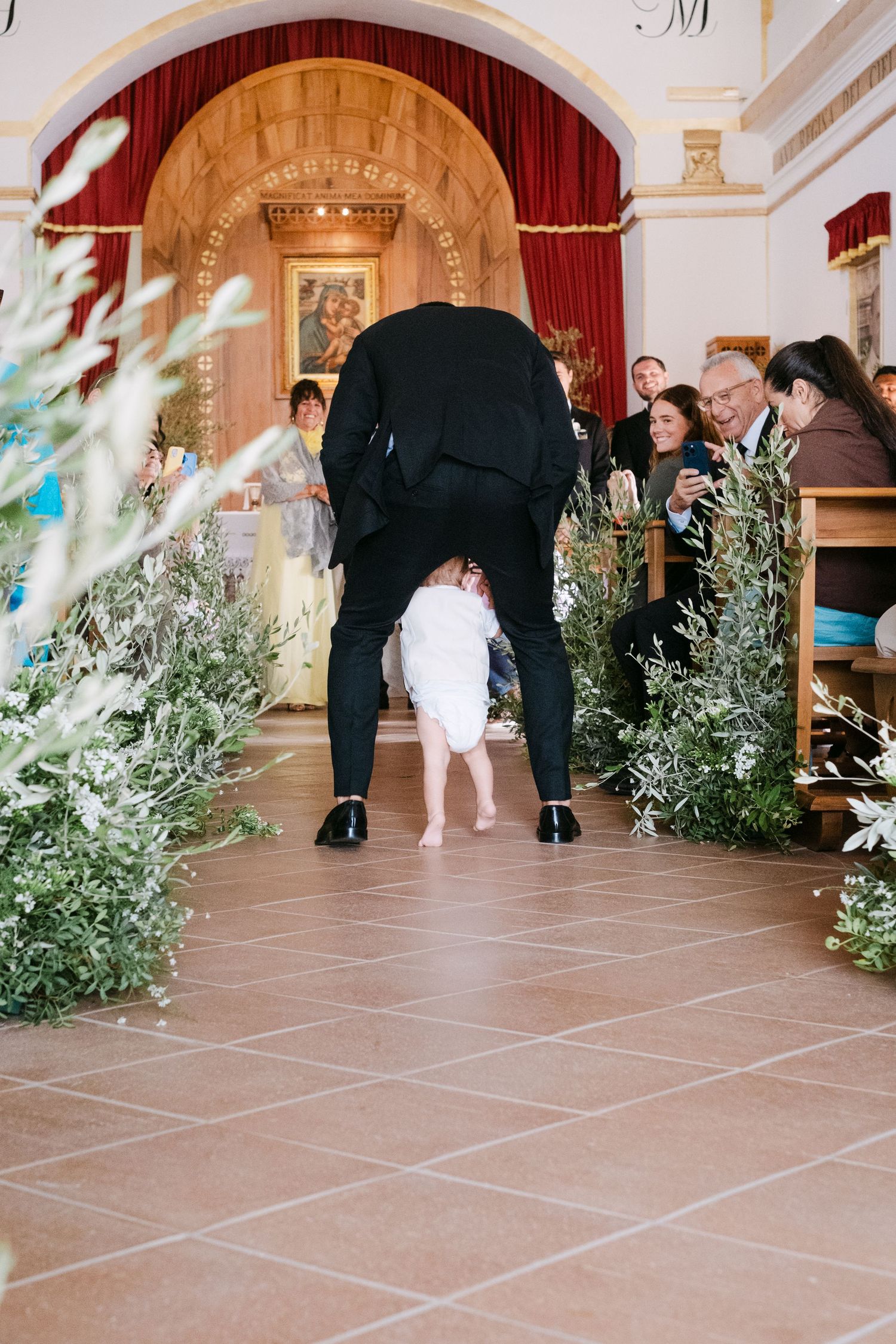 Wedding ceremony setup with olive branches and floral decorations in an elegant indoor venue.