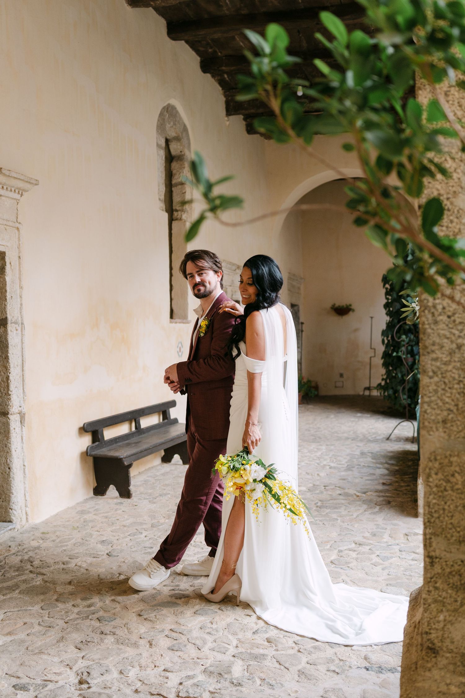 Playful wedding photo sequence in a rustic stone archway with bride in flowing white dress.