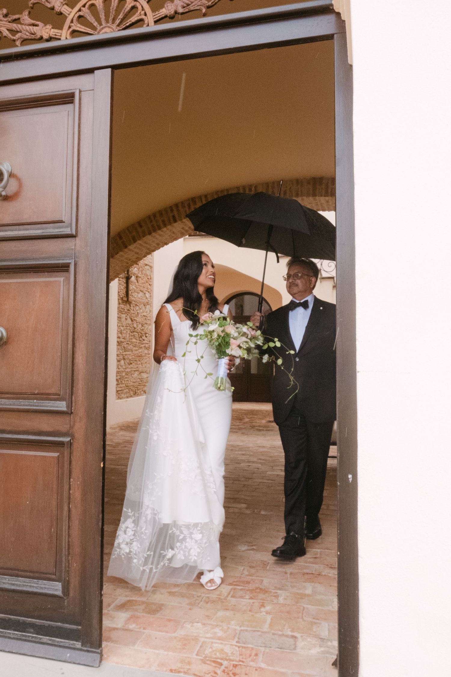 Wedding couple shares intimate moment under stone archway during ceremony.
