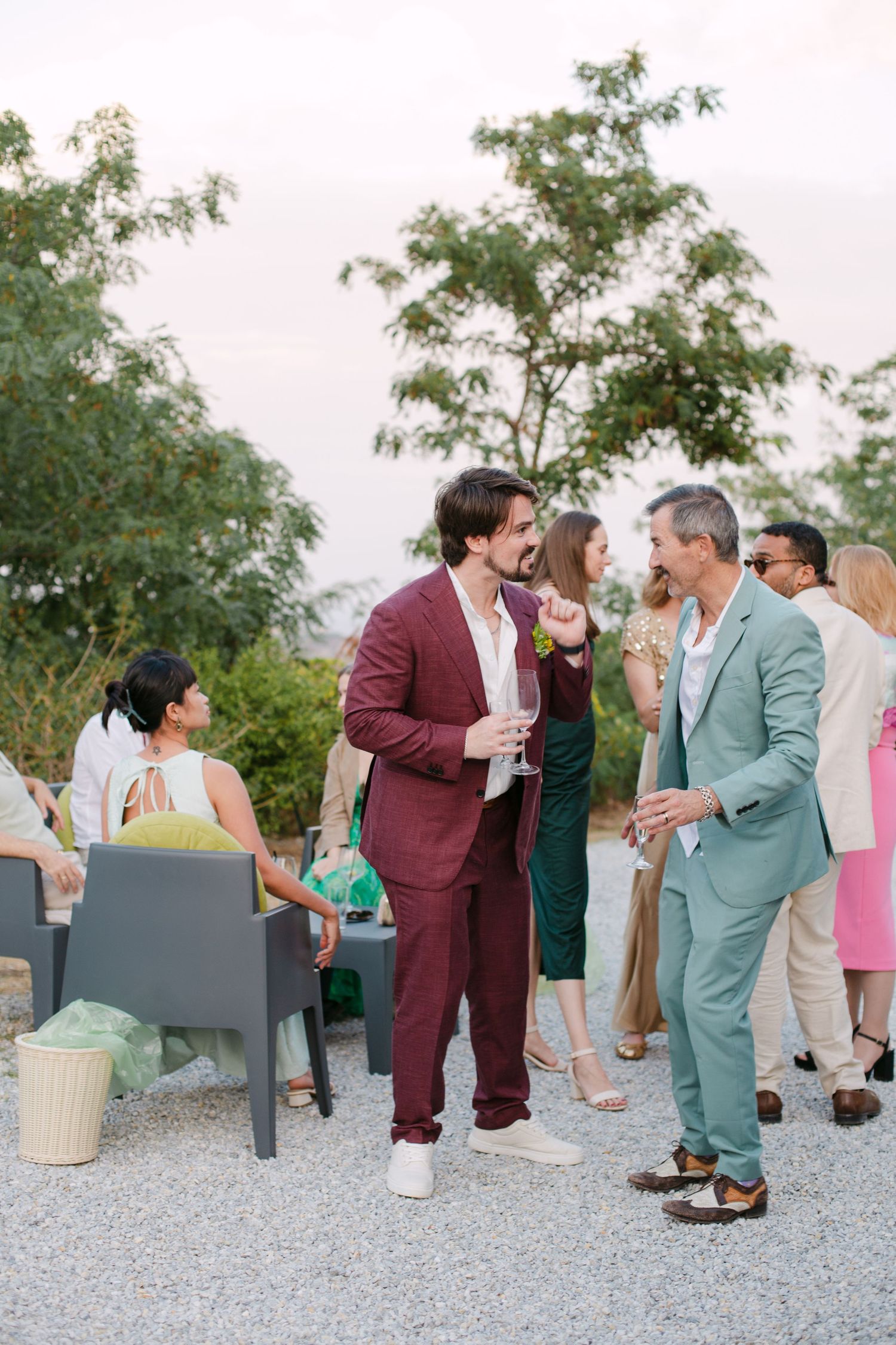 Wedding guests in colorful attire socialize during an outdoor reception.