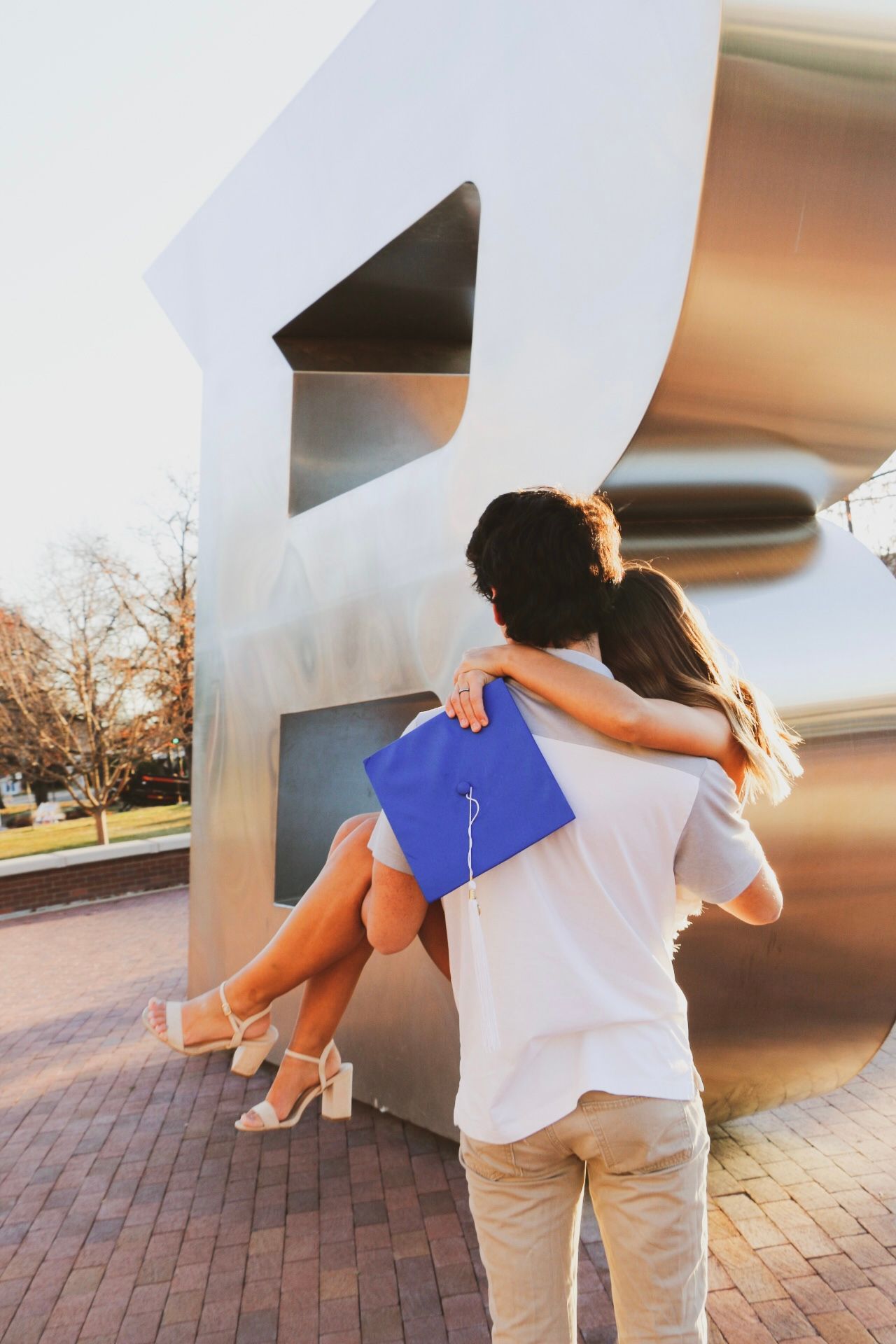 Graduation photoshoot with large white numeral sculpture on brick plaza.