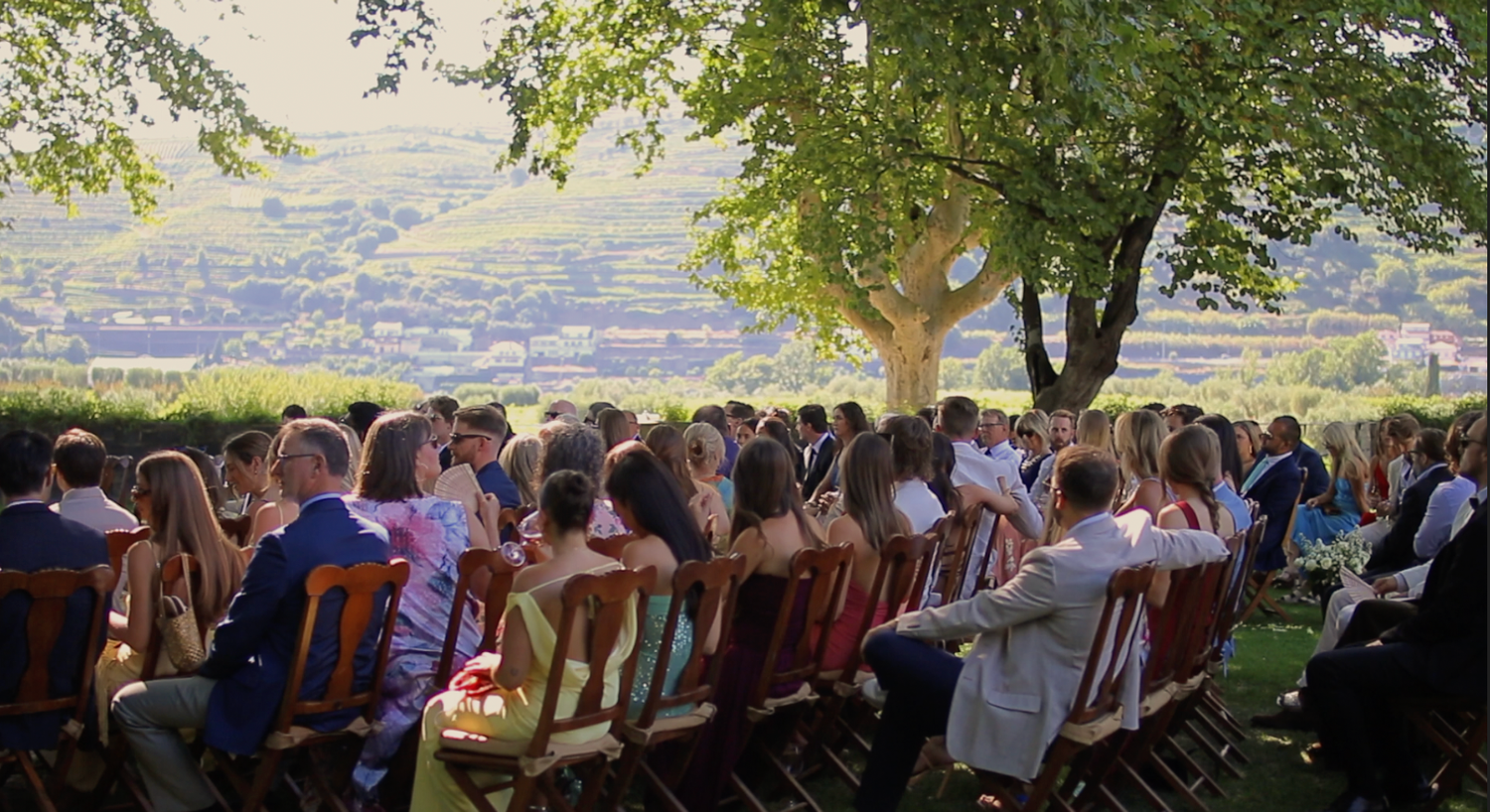 Wedding guests seated outdoors overlooking a scenic valley view.