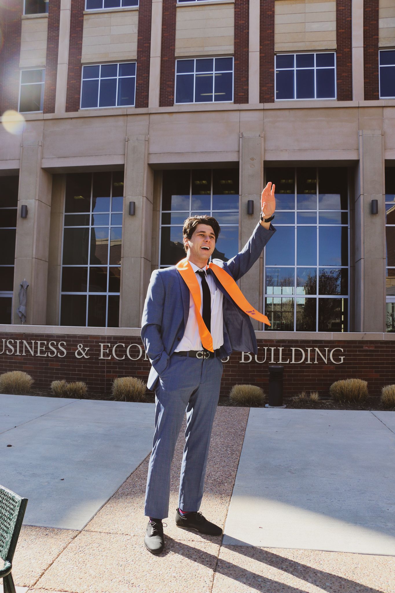 Person in business suit celebrating outside the Business and Economics building.