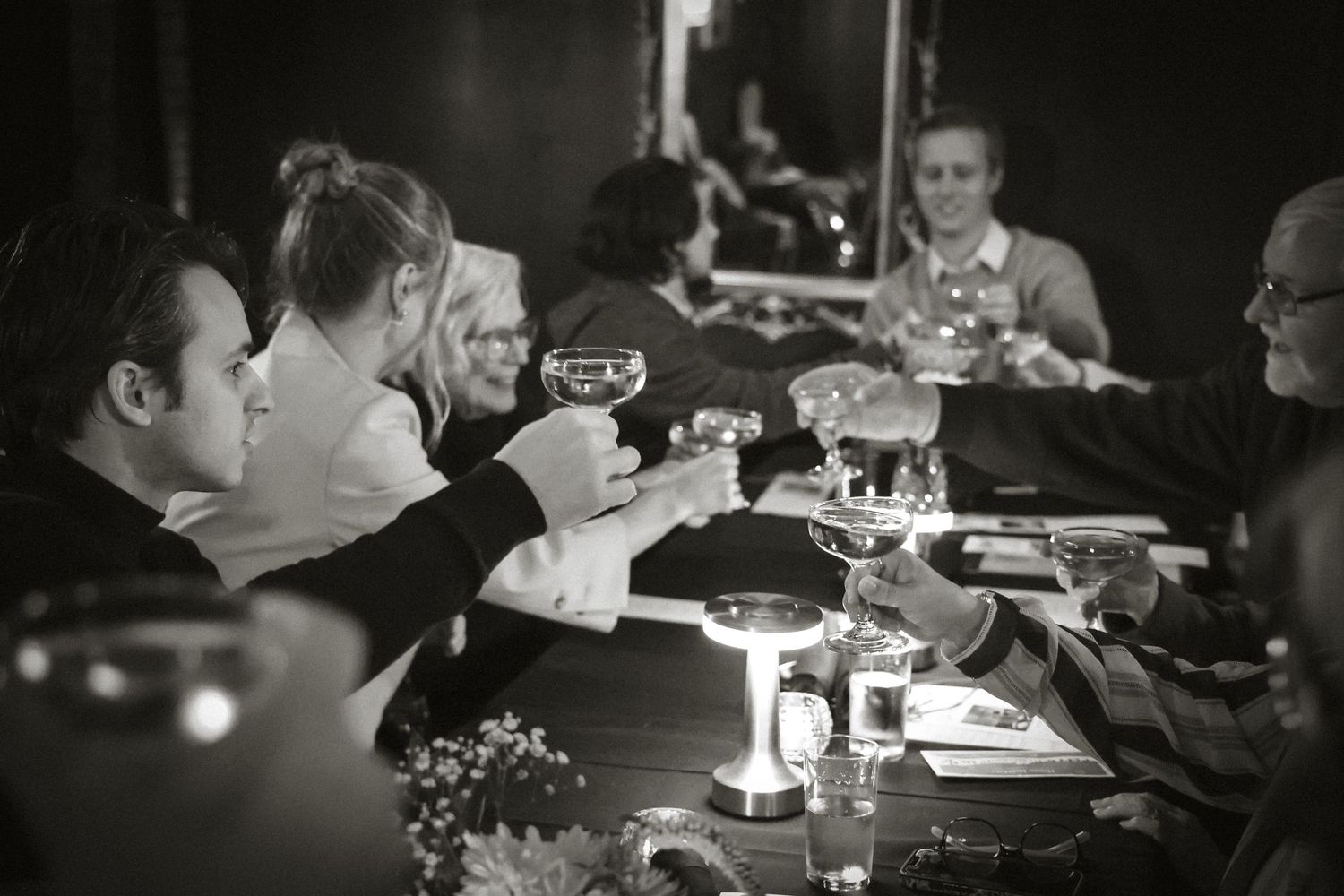 A black and white photo of people dining at a candlelit restaurant table.