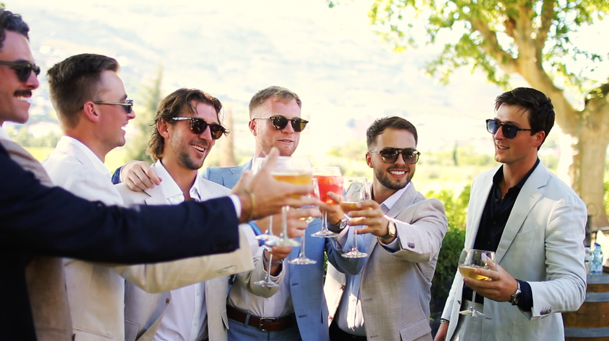 Wedding guests mingling and toasting with drinks at an outdoor reception.