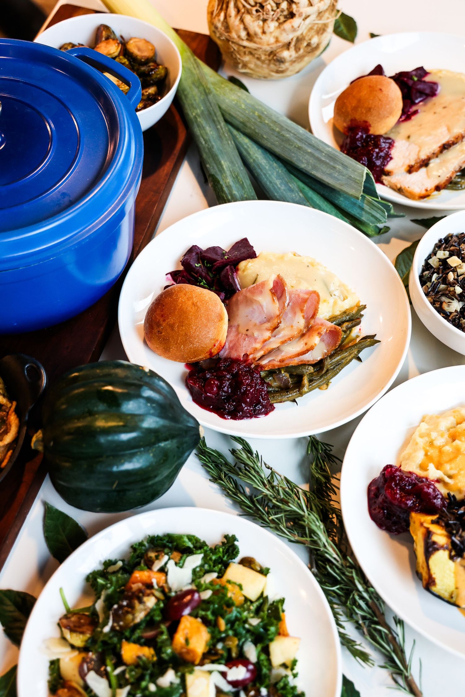 Variety of plated dishes with roasted vegetables and sides served on white dinnerware.