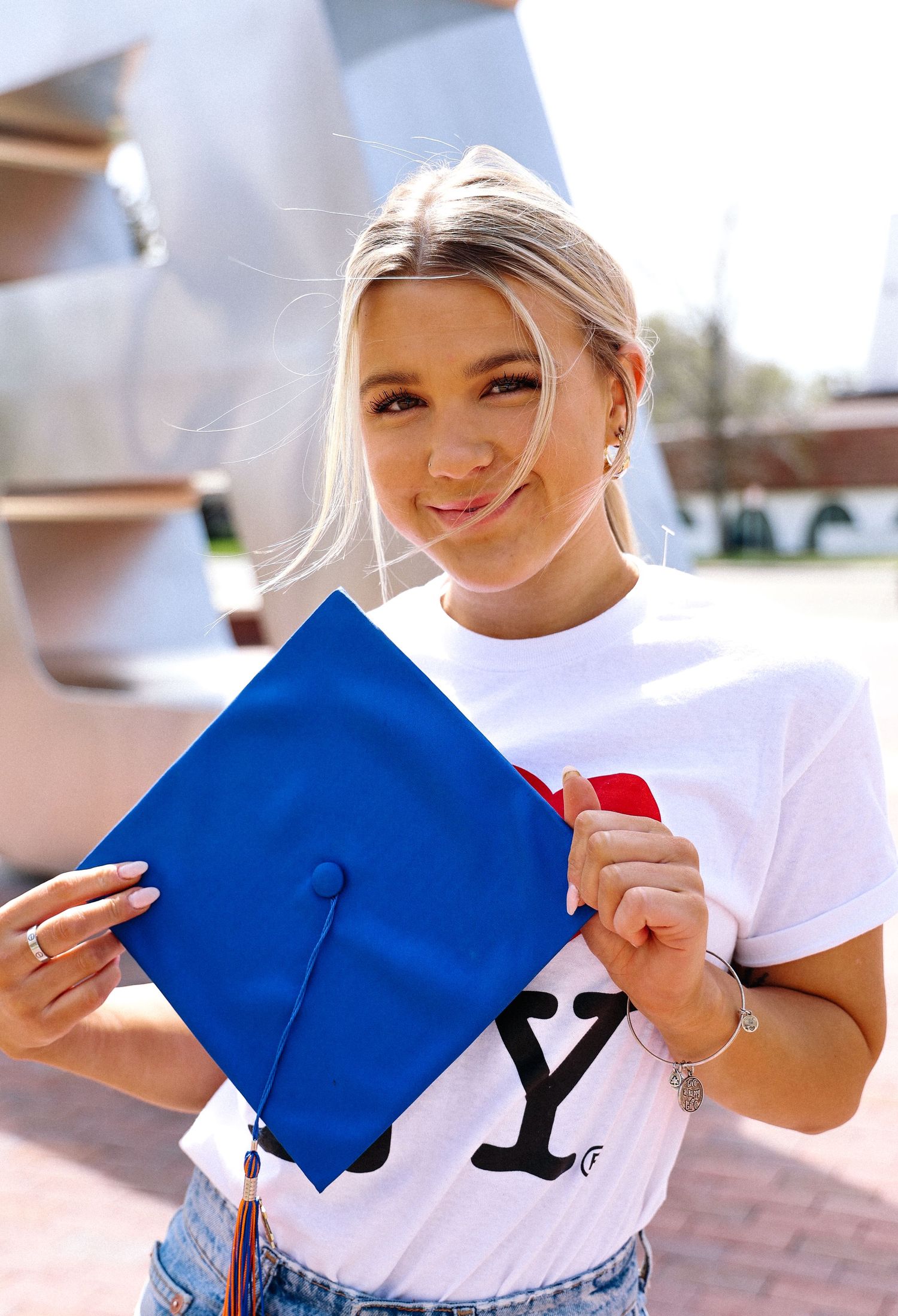 Person holding and tearing blue graduation cap in celebratory photo sequence.