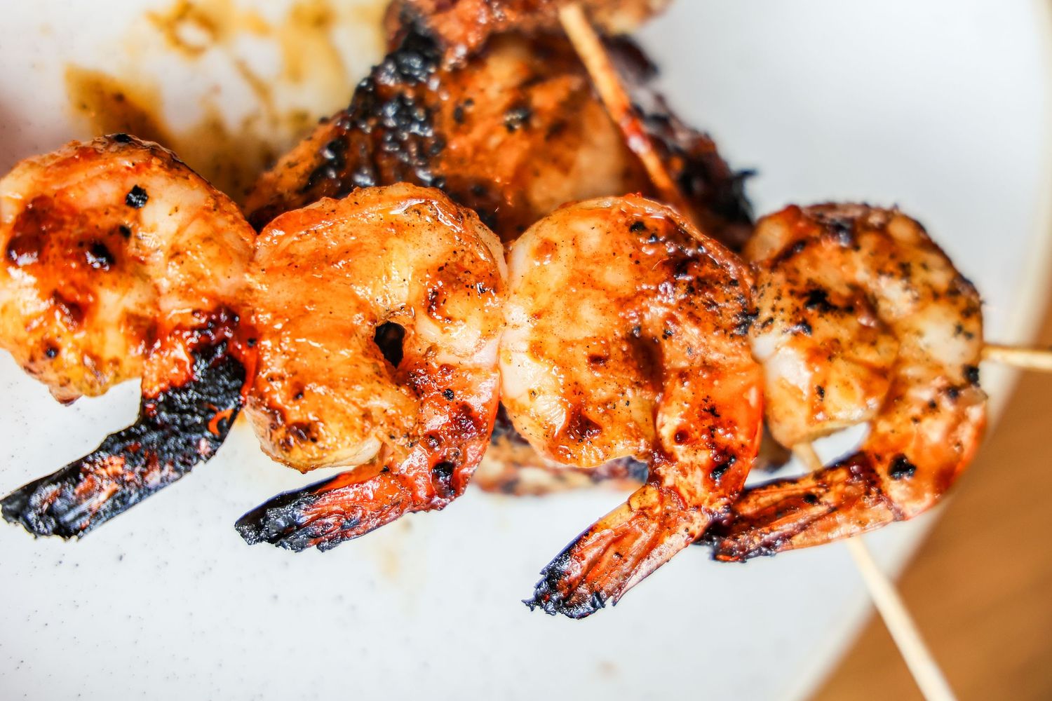 Grilled shrimp skewers with charred edges on a white surface.