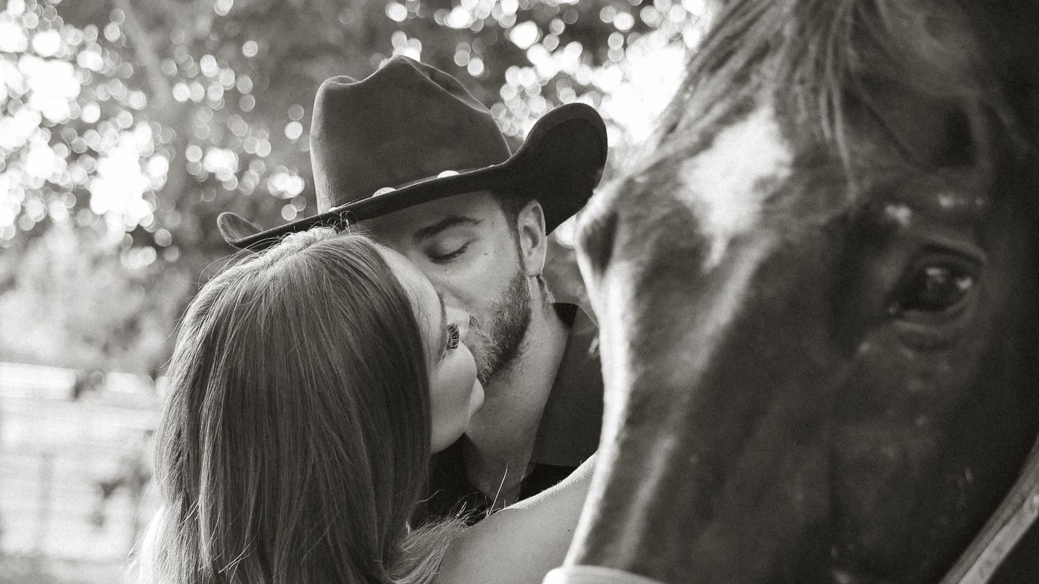 Horse stable photoshoot featuring couple in black and white tones.