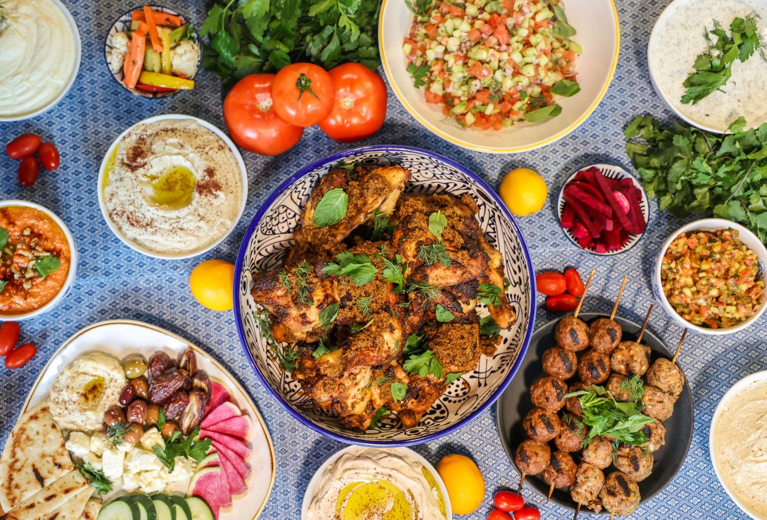 Overhead view of a Mediterranean feast spread with various dishes, dips, and fresh vegetables.