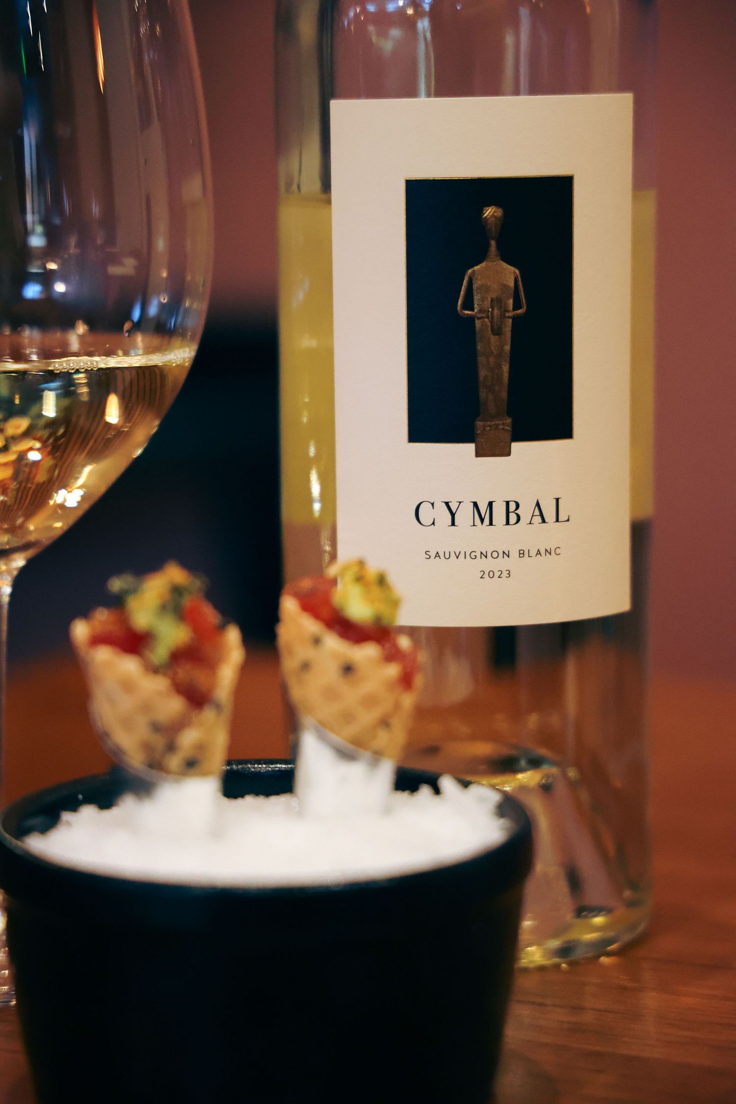 Cymbal Sauvignon Blanc 2023 wine bottle displayed with mini waffle cone appetizers on ice.