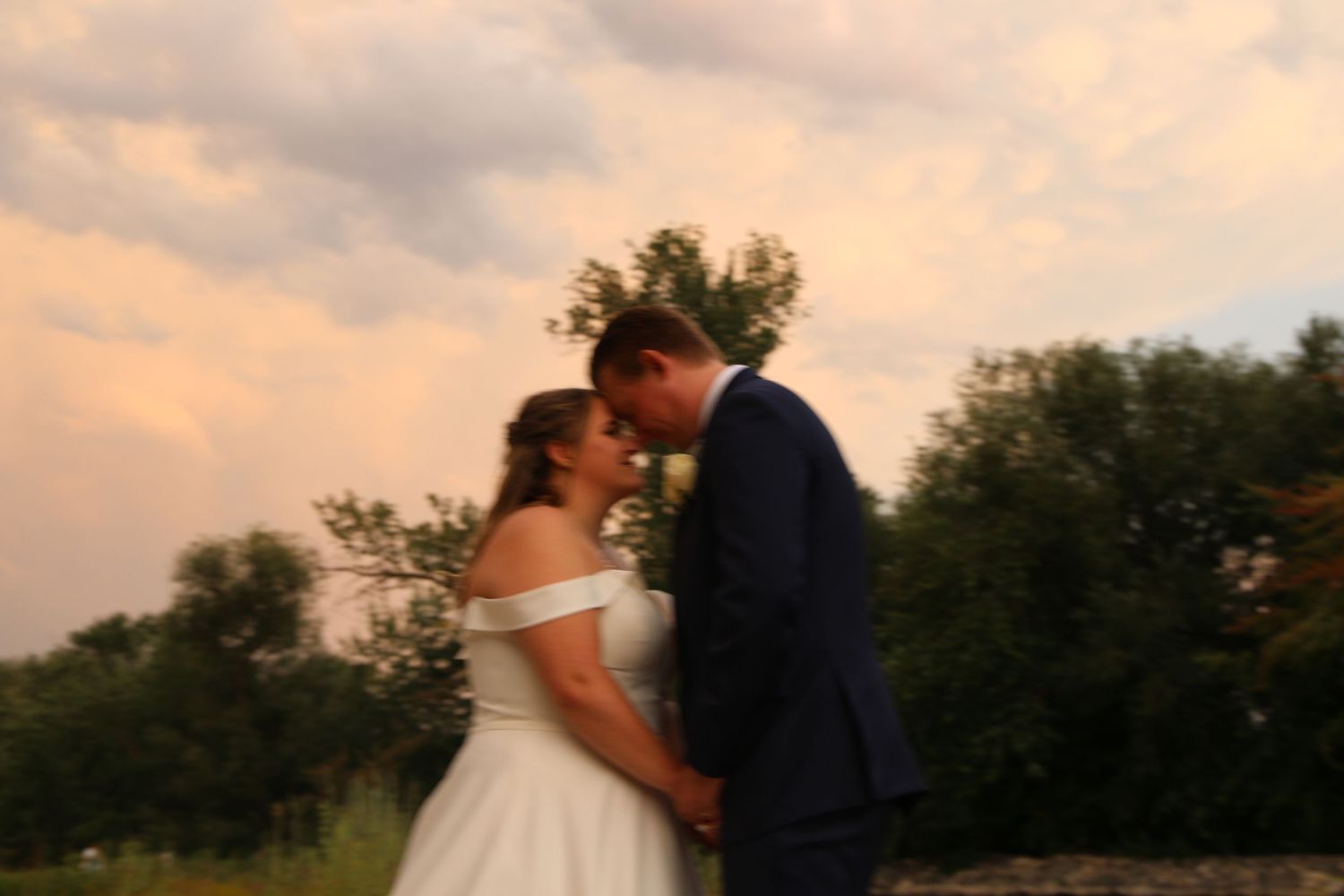Romantic wedding couple embraces during sunset golden hour.