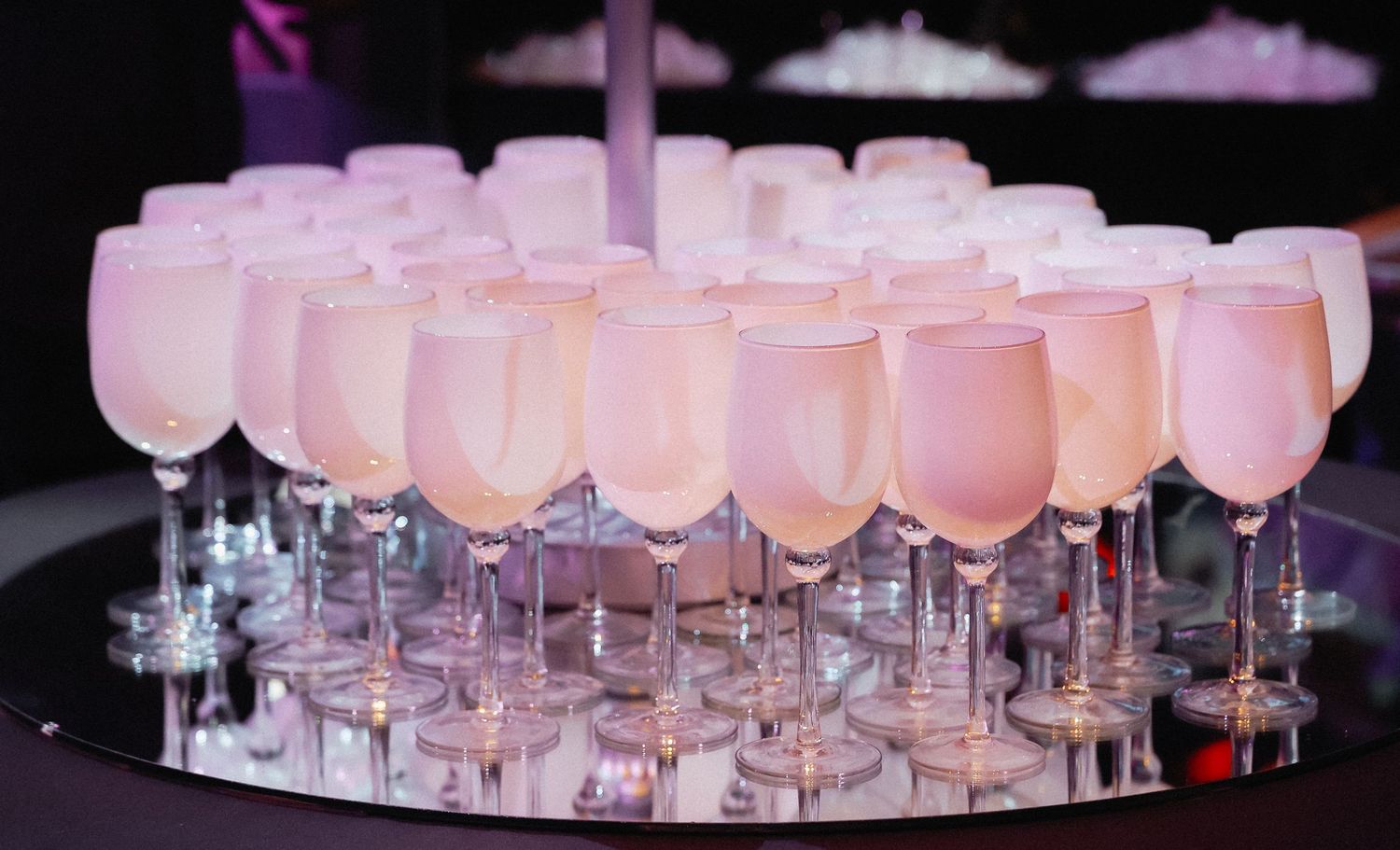 Row of pink cocktails on glass stands arranged for elegant event.