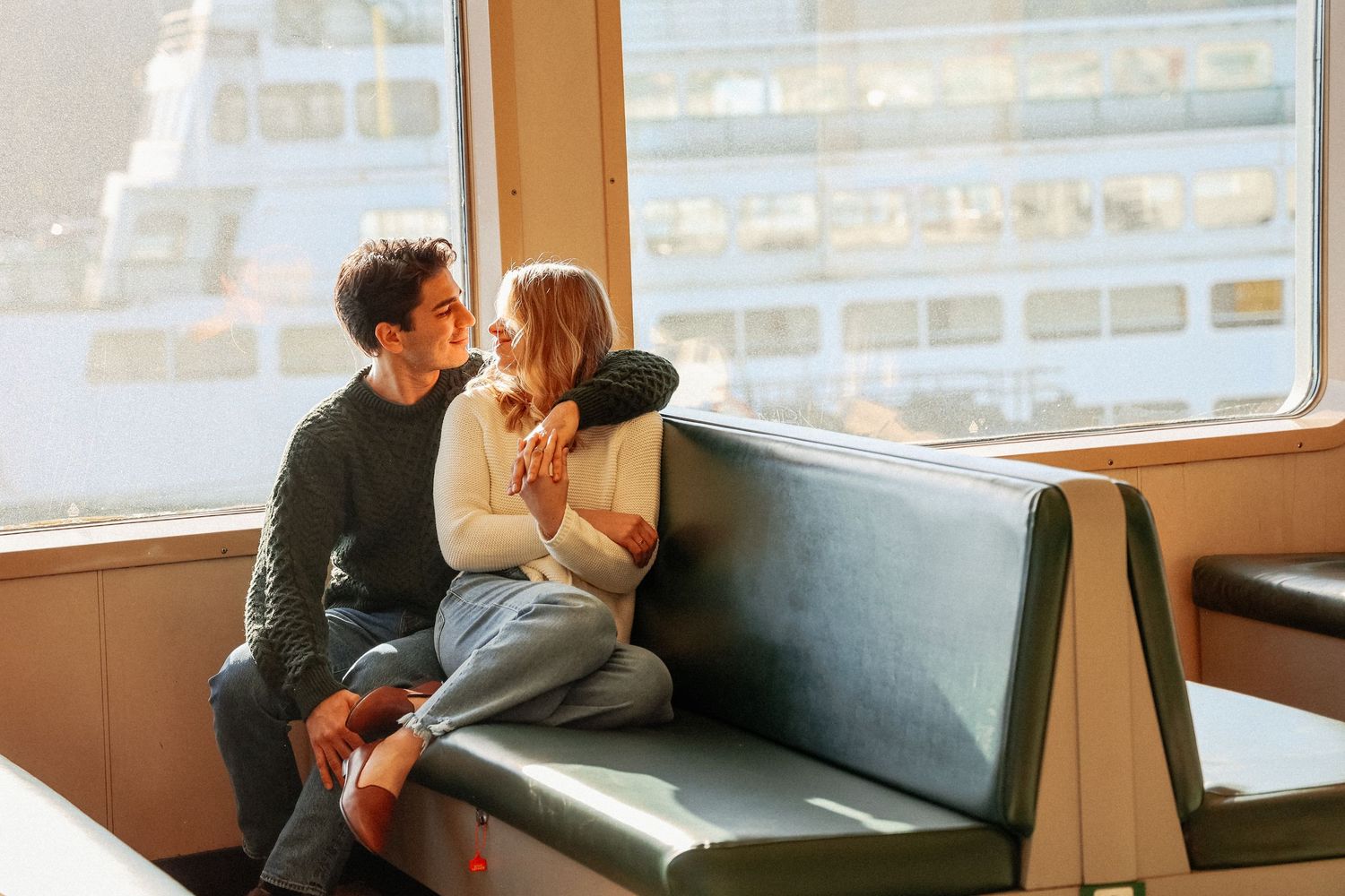 Romantic couple shares intimate moments on a couch by large windows in an urban setting.