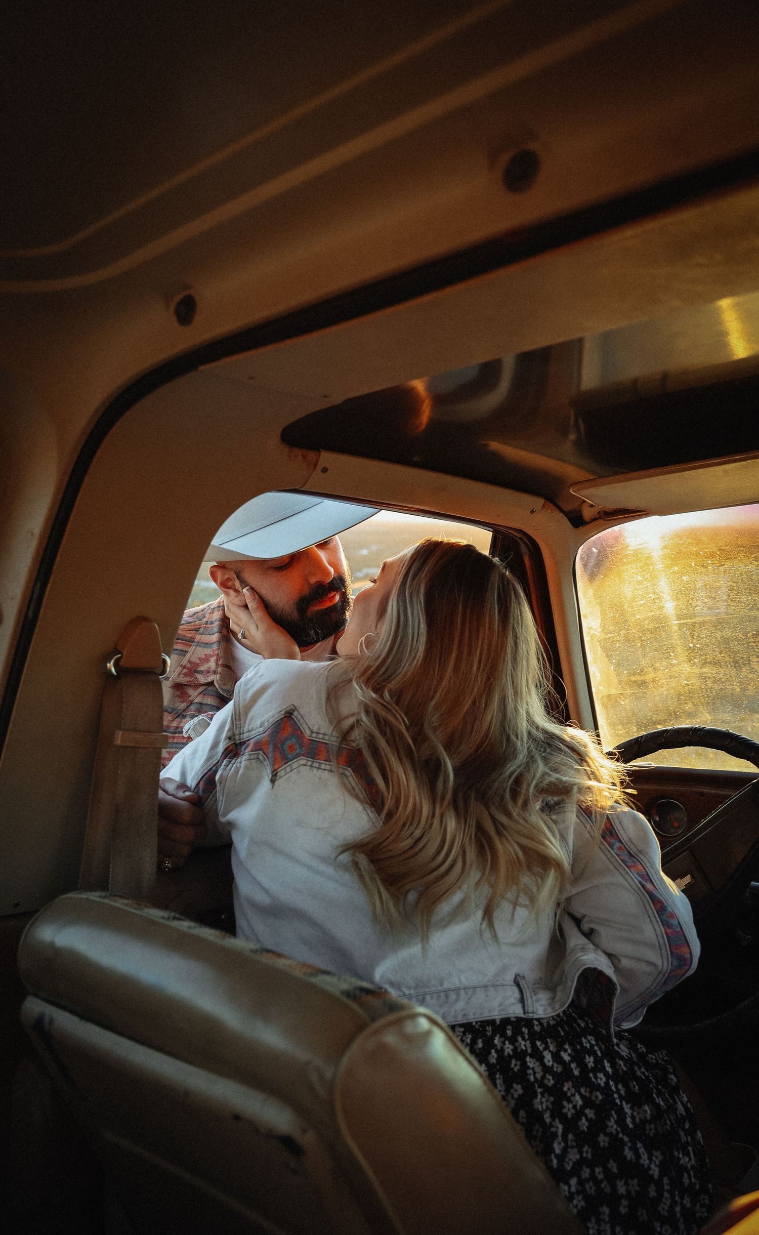 Couple sharing intimate moment inside vintage truck at sunset.