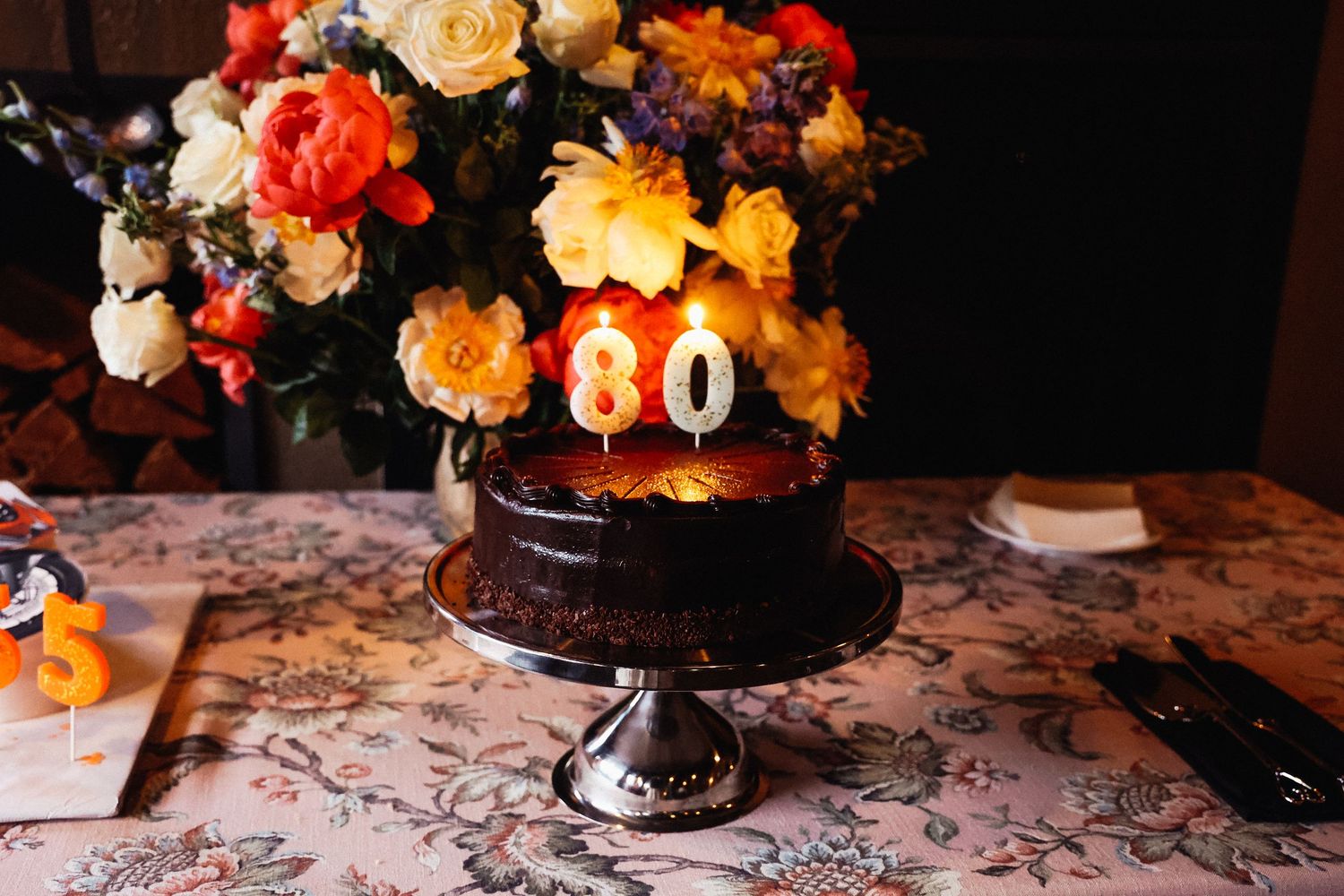 Elegant floral arrangement with orange and peach roses on patterned tablecloth.