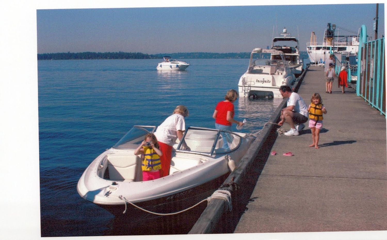 People in life jackets boarding small boats at a busy marina dock on a calm sunny day.