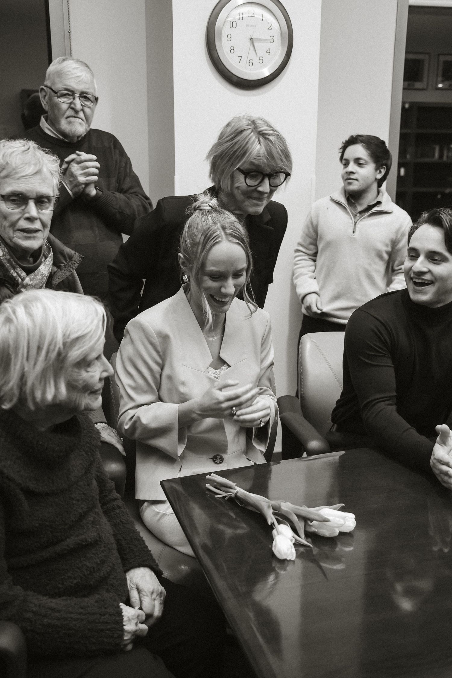 Black and white photo of a group gathered around a conference table during a meeting.