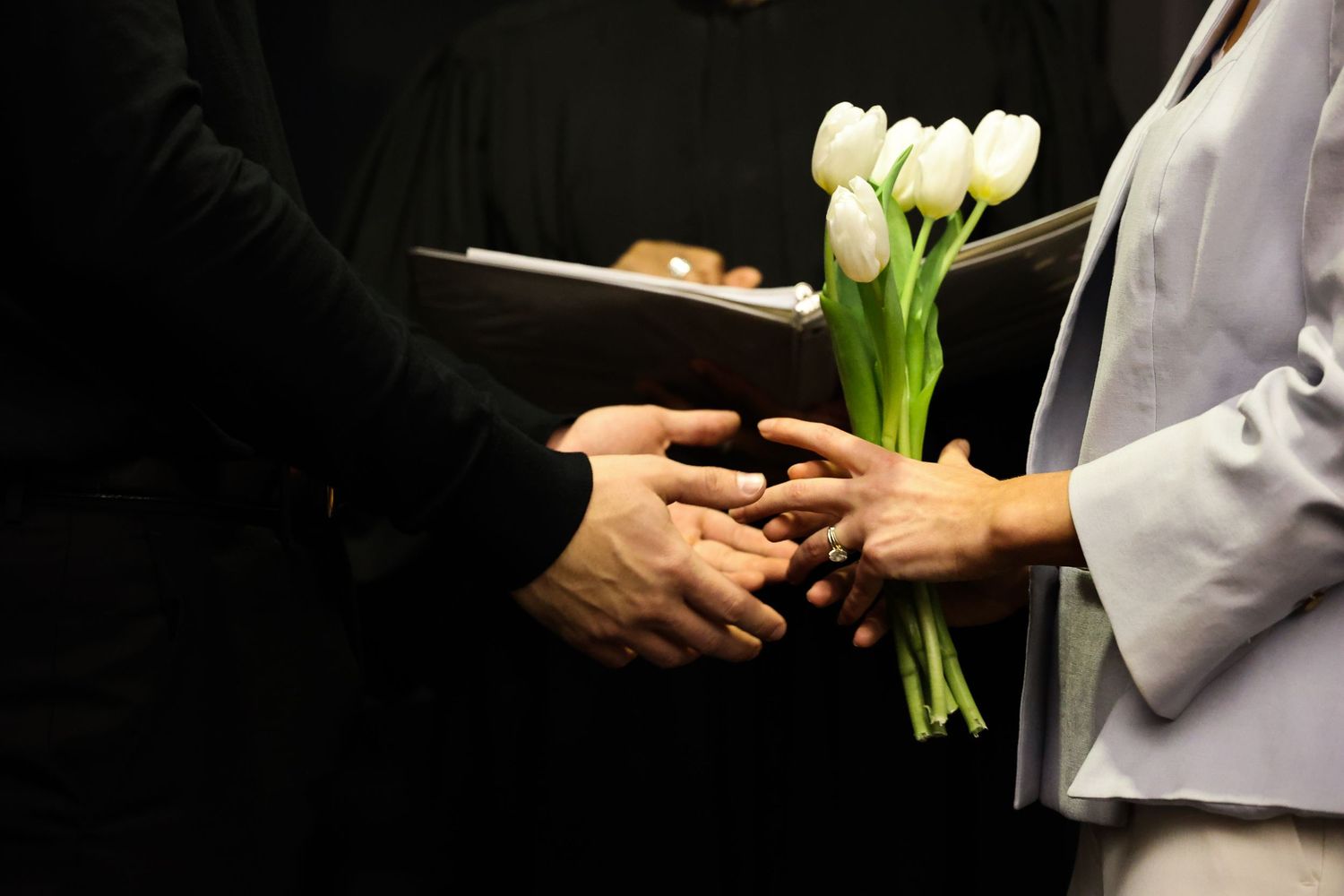 Close-up of hands exchanging wedding rings during ceremony.