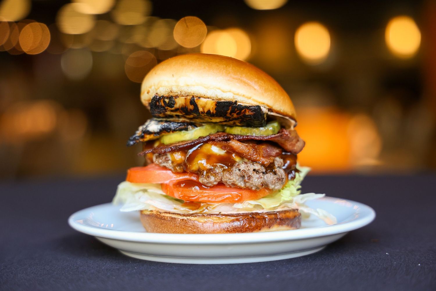Gourmet burgers with toppings photographed in warm lighting against dark background.