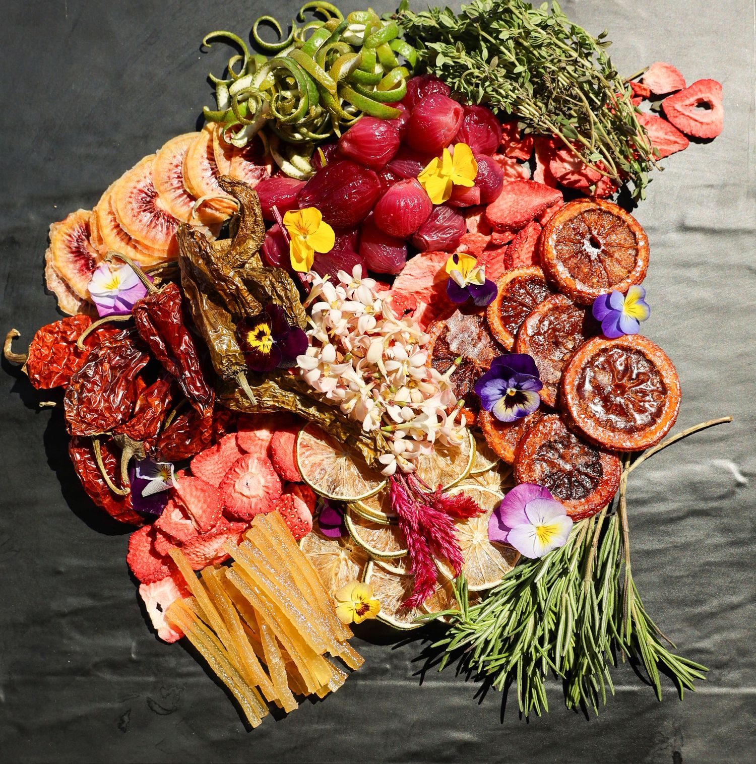 Artfully arranged charcuterie board with edible flowers and colorful garnishes.