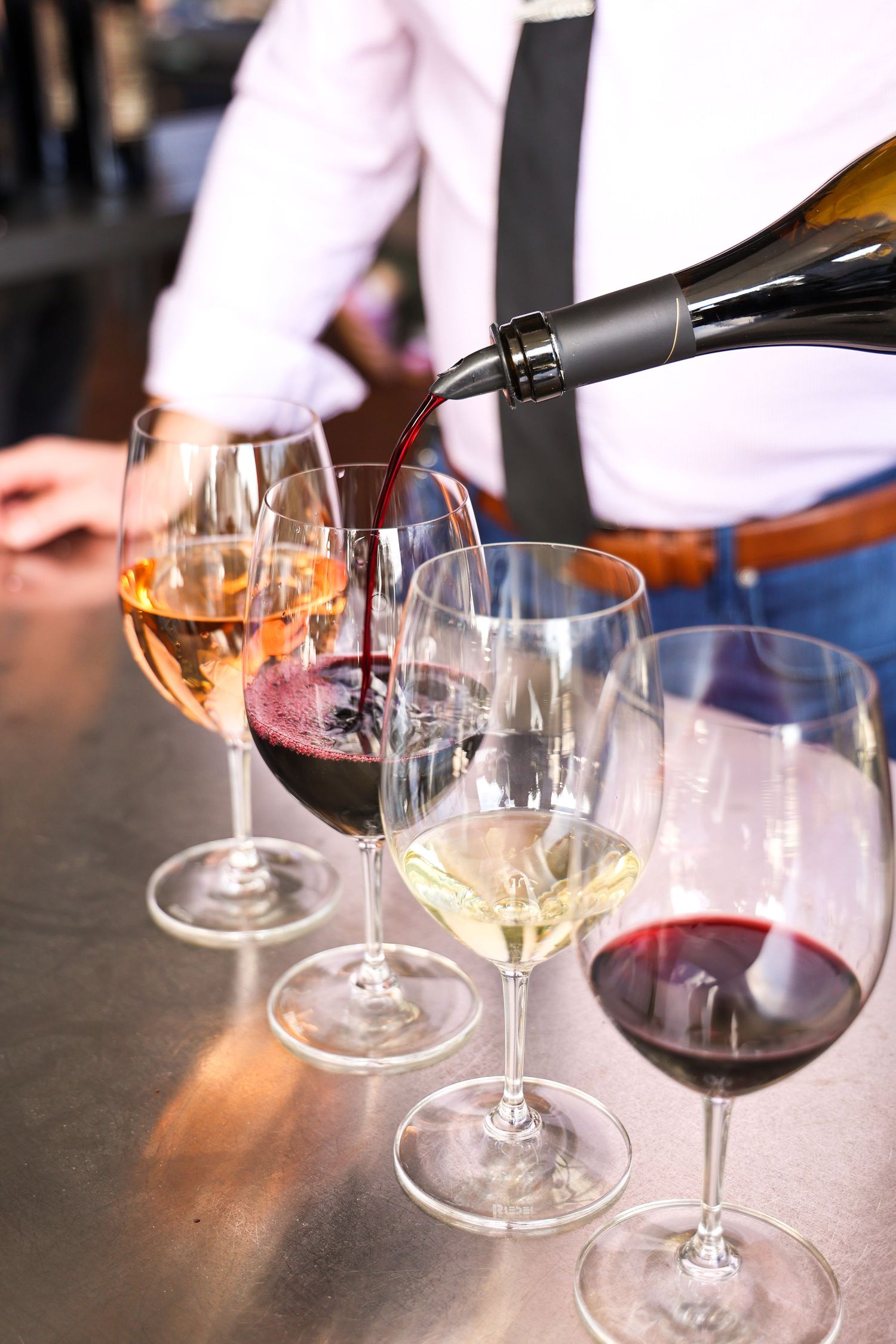 Wine being poured into elegant crystal glasses at a tasting event.