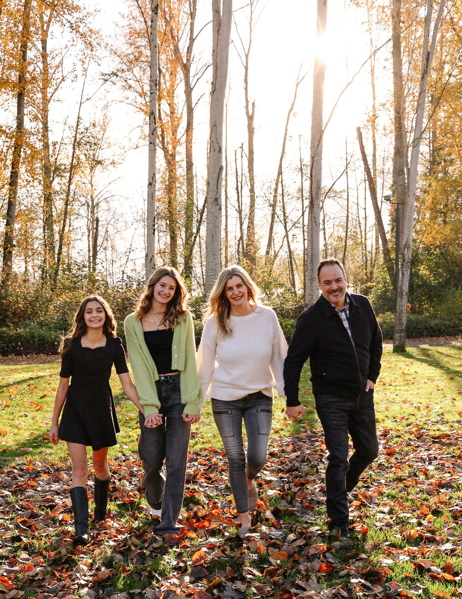 Group walking together through fallen autumn leaves in a wooded area.