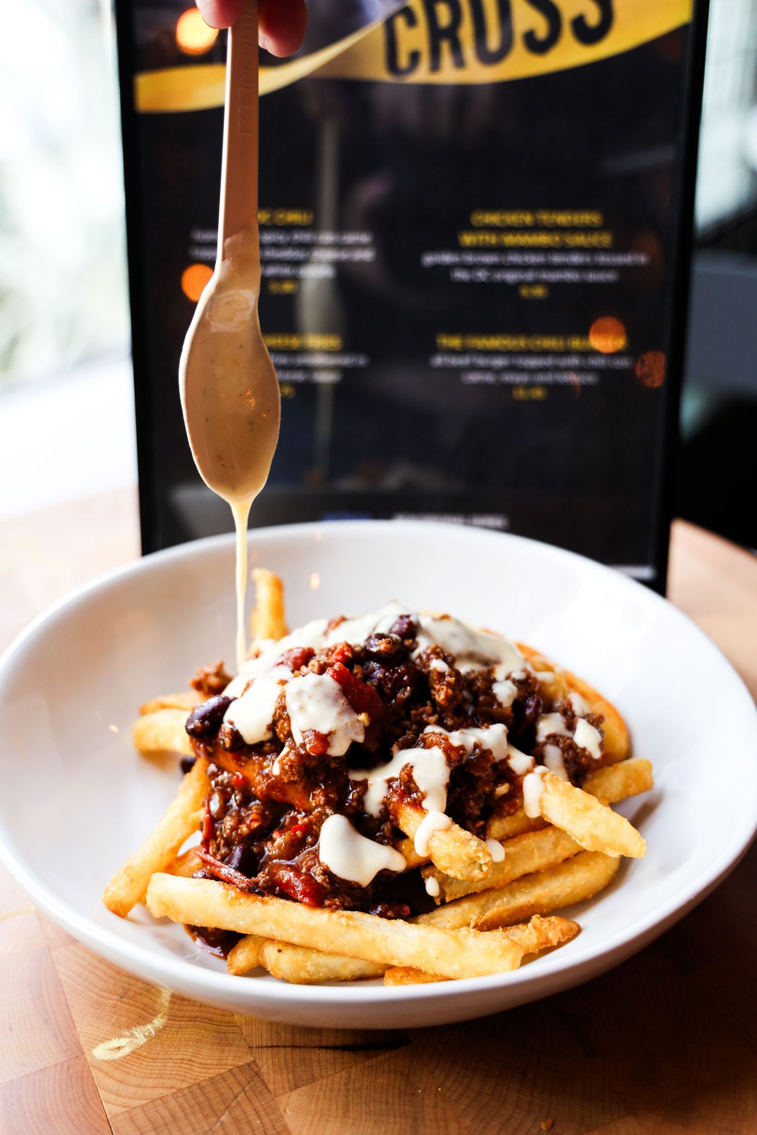 Loaded french fries topped with savory meat sauce and melted cheese on white plates.