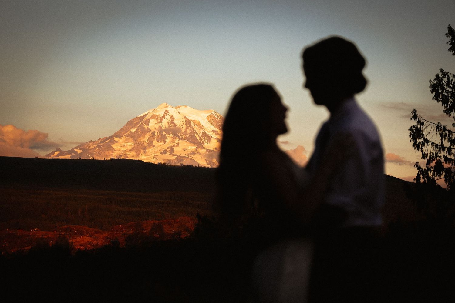 Silhouettes against a dramatic mountain sunset with warm orange glow.