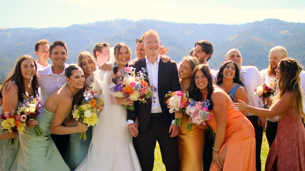 Wedding guests gathered outdoors with mountain scenery in the background.