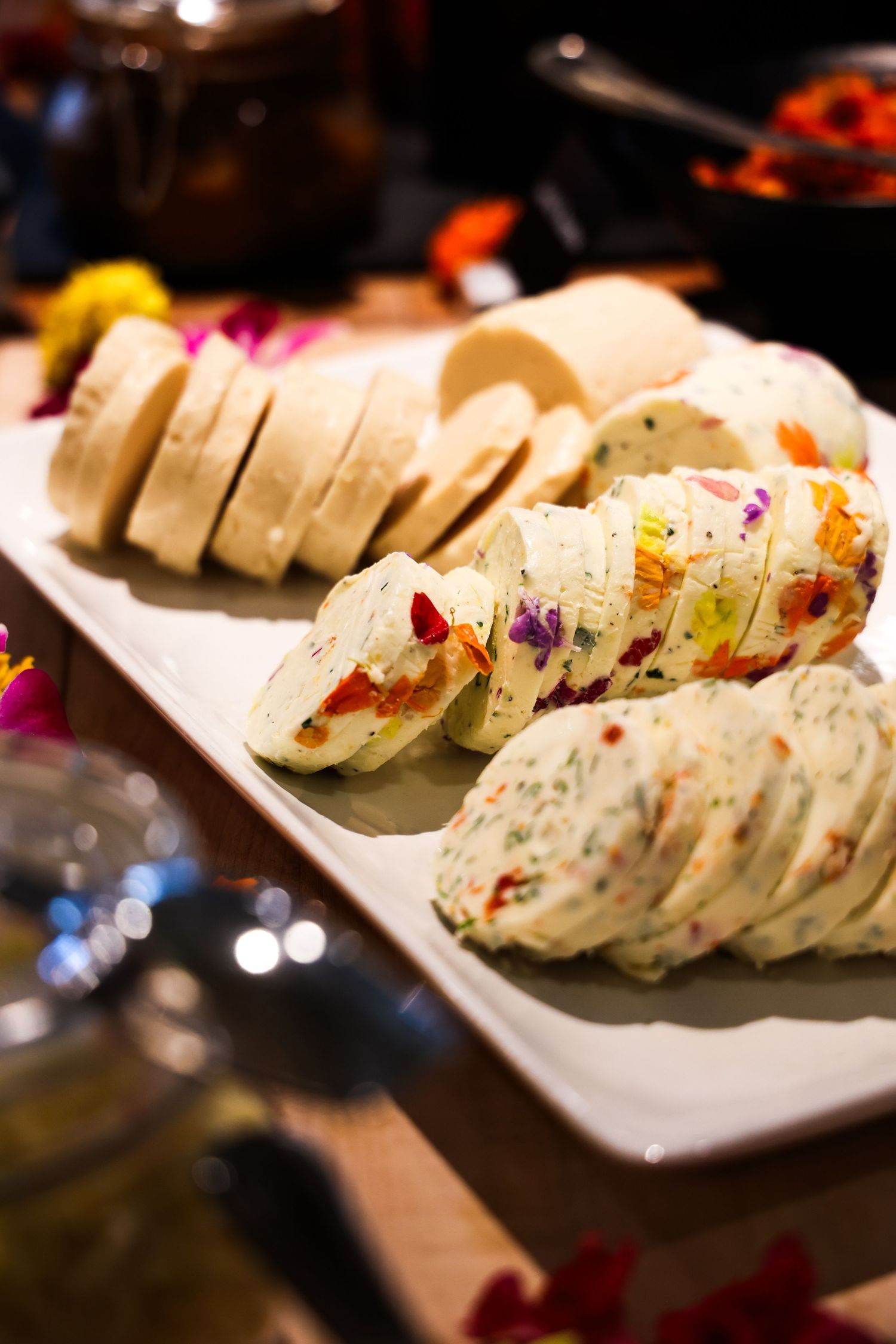 Colorful wrapped tortilla pinwheels arranged on white serving platter.