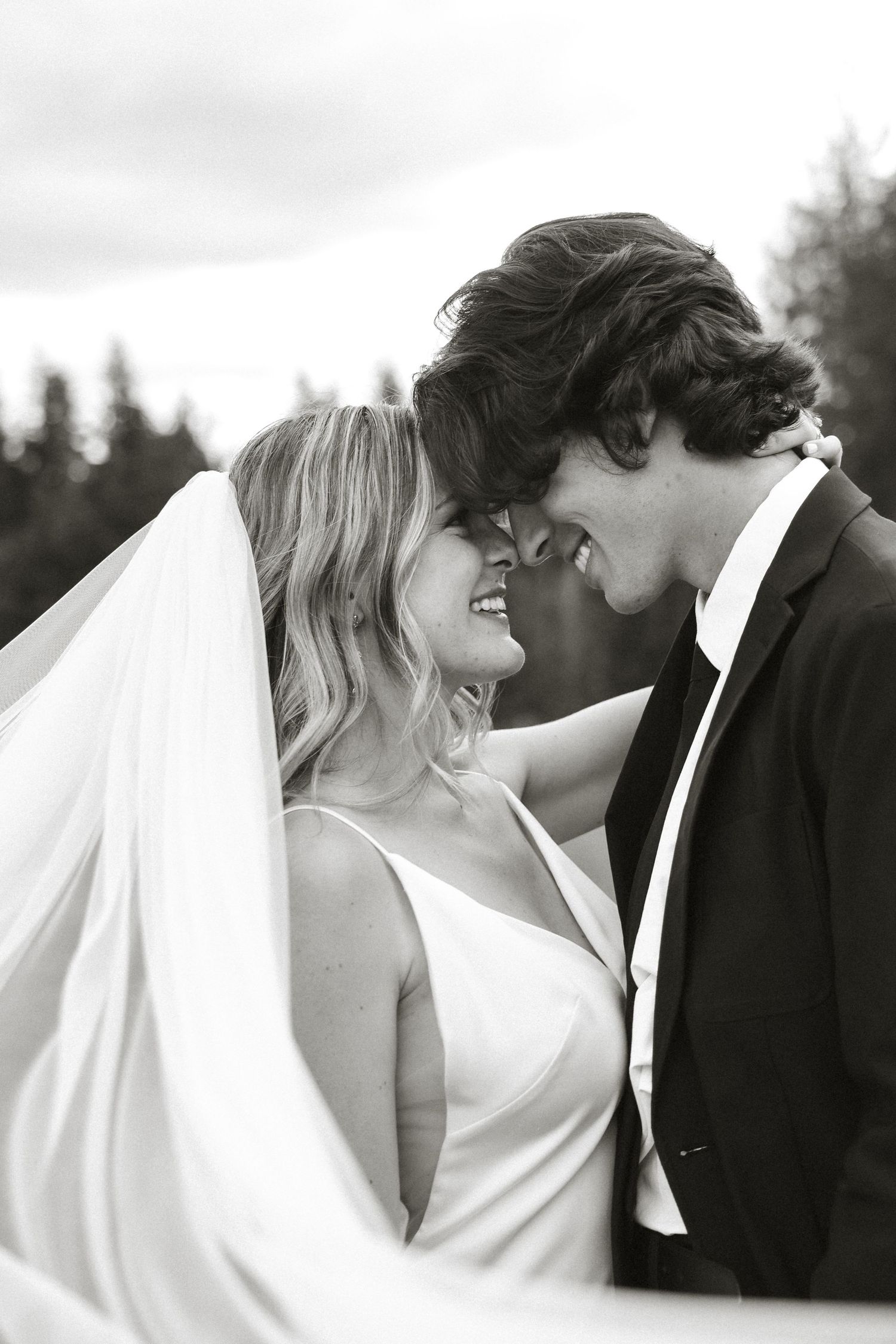 Wedding couple sharing intimate moments under a flowing white veil.
