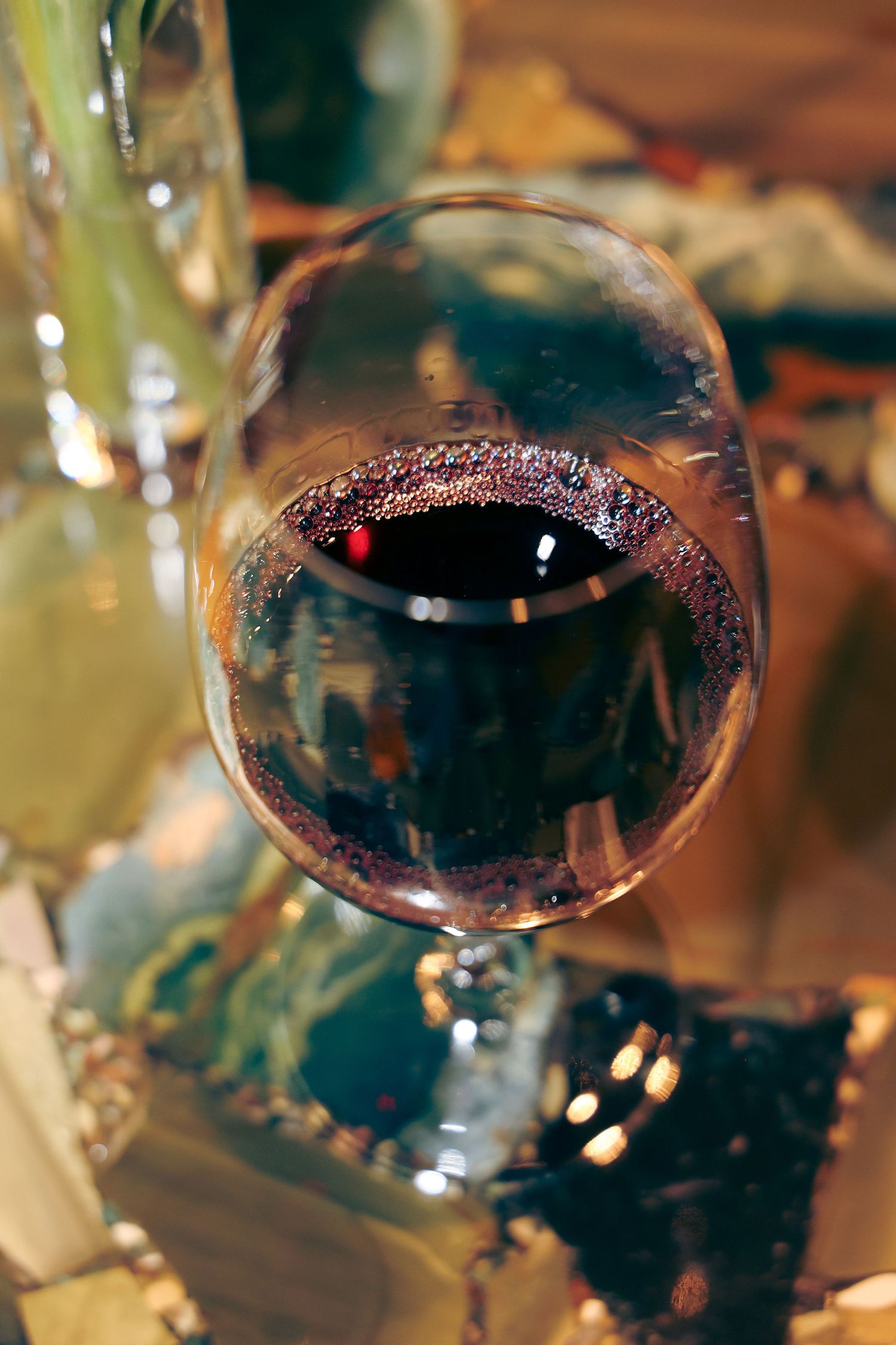 Close-up view of red wine in glasses with sparkling reflections and bokeh lights in the background.