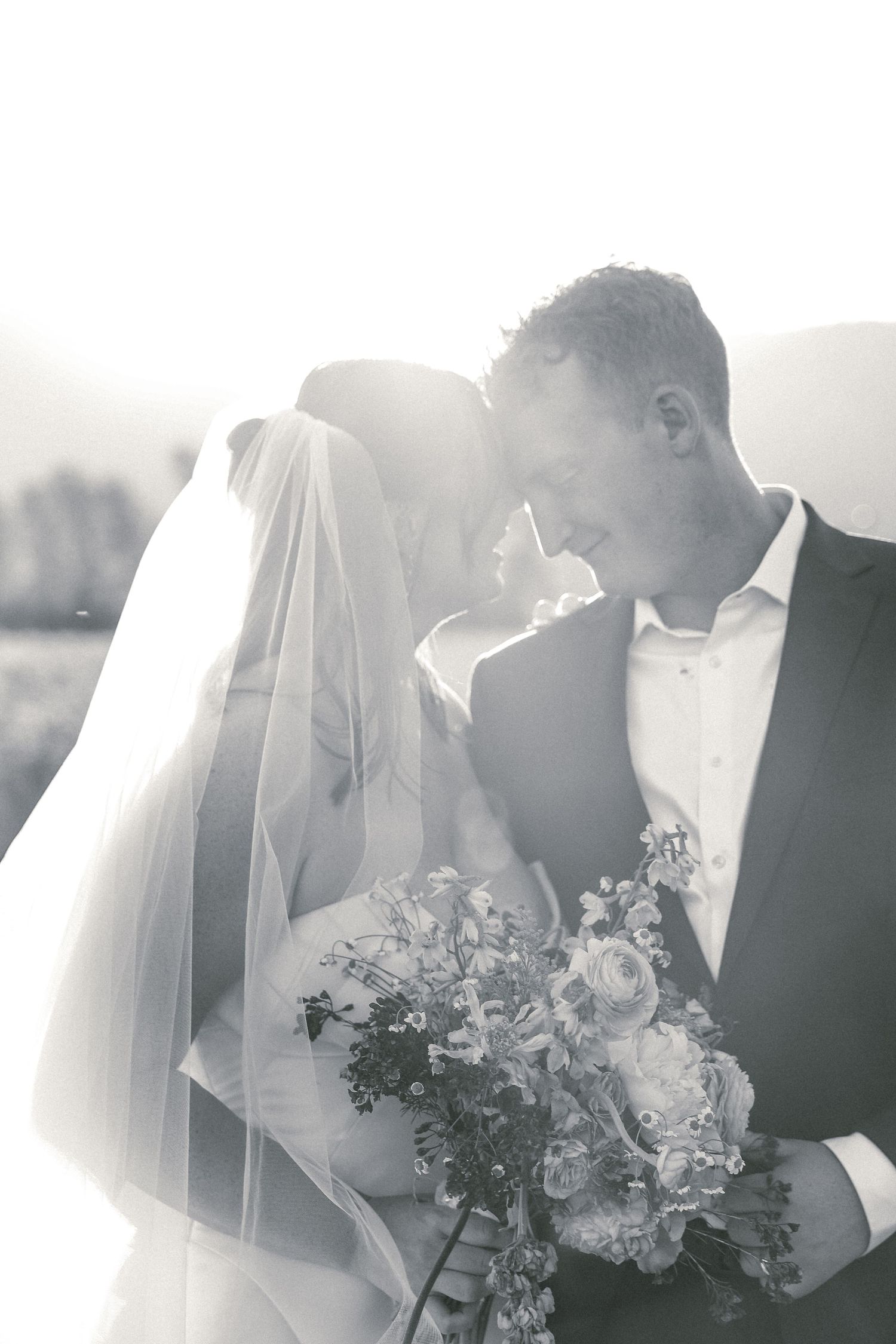 Intimate black and white wedding portraits with flowing veil and floral bouquet.