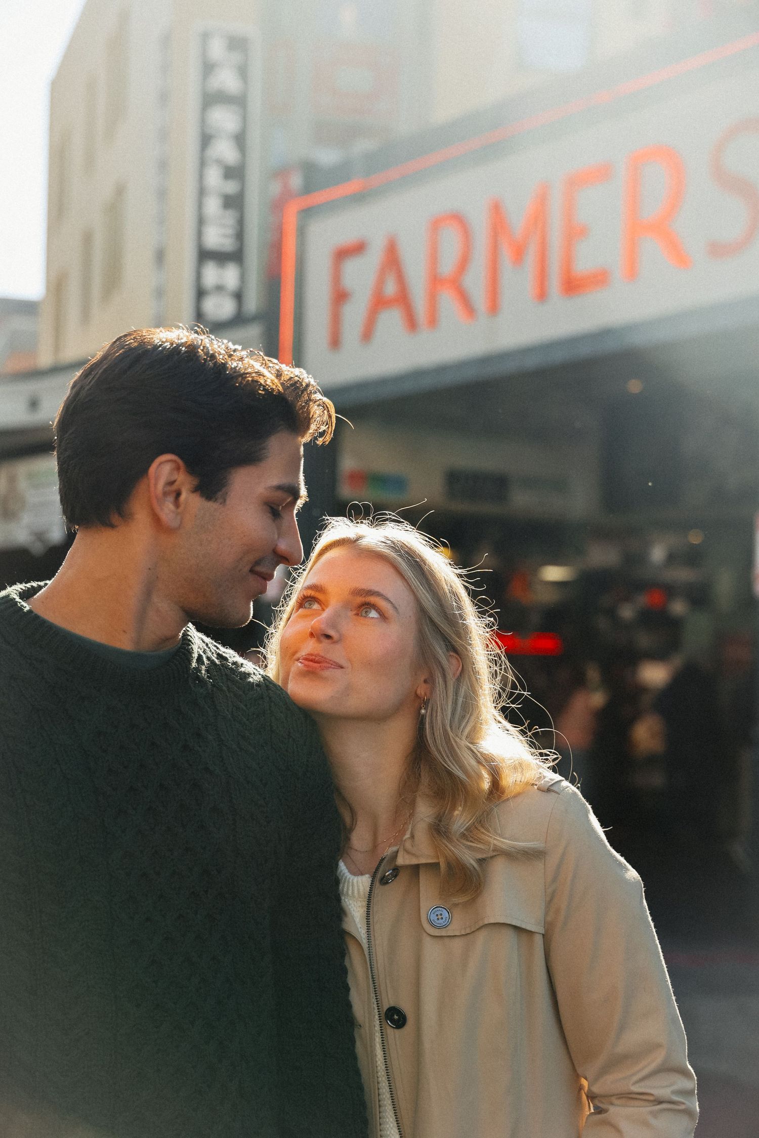 A romantic couple shares a sweet moment outside a city storefront.